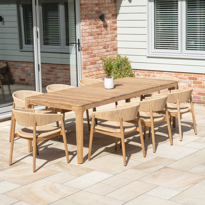 Outdoor dining is elevated with the Lucca 8 Seat Dining Set with Teak Table in Natural Weave—an elegant ensemble with a wooden table and eight chairs, ideal for any patio near a home’s large windows.