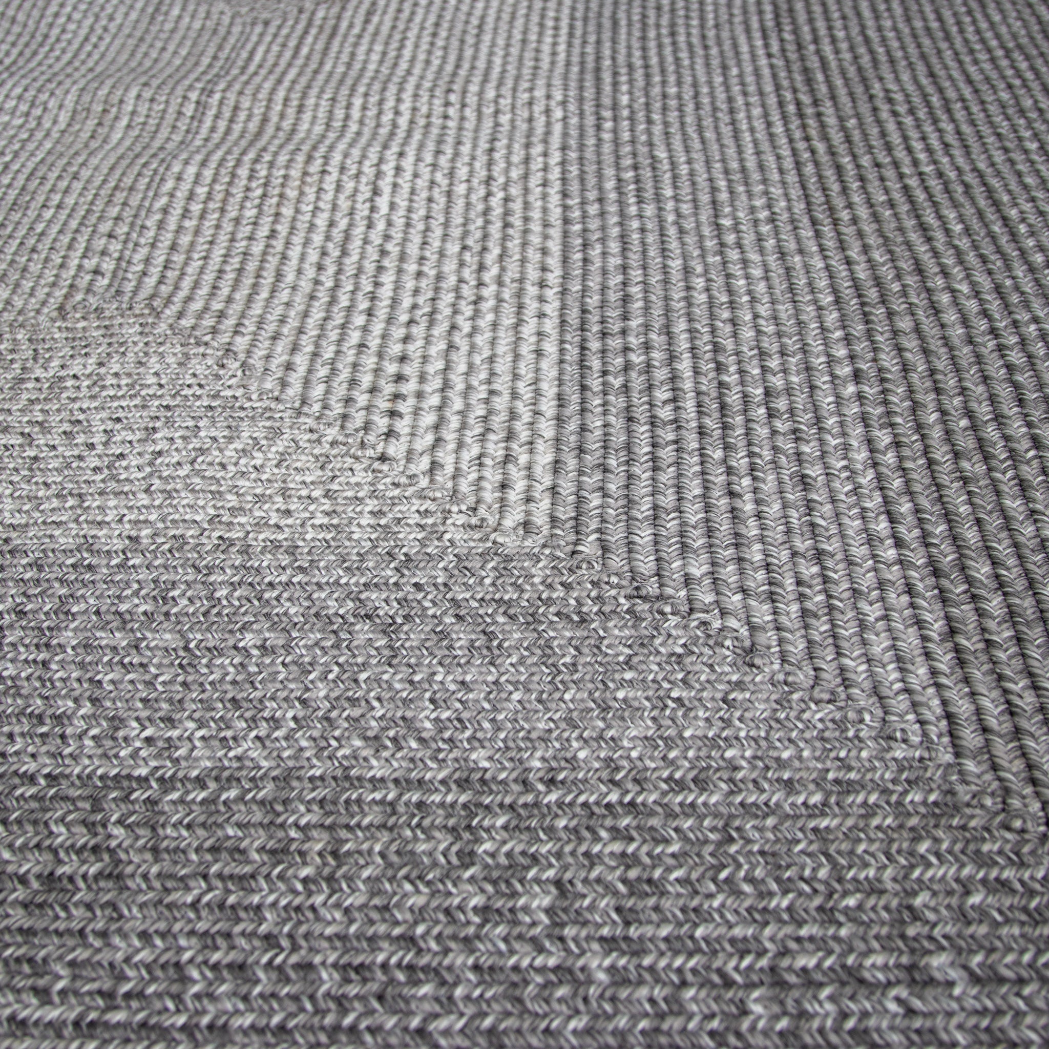Close-up of the Hestia 220cm x 160cm Weatherproof Indoor and Outdoor Rug in Walnut Grey, showcasing its textured pattern and intricate UV-resistant threads.