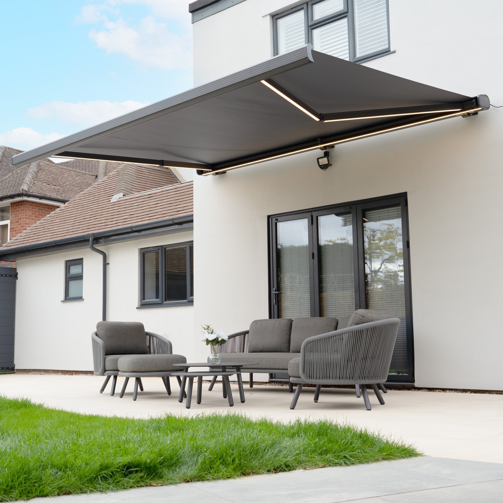 A Dekota 3 seat sofa set in grey underneath an LED awning