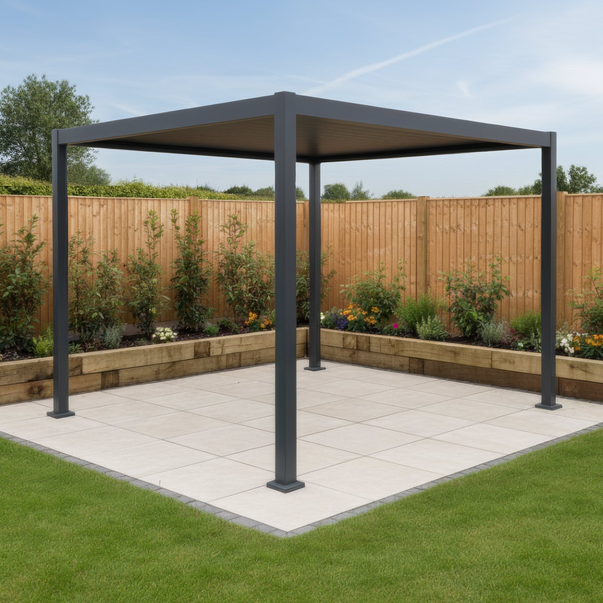 A modern metal pergola stands on a tiled patio in a landscaped backyard with flowers and a wooden fence.