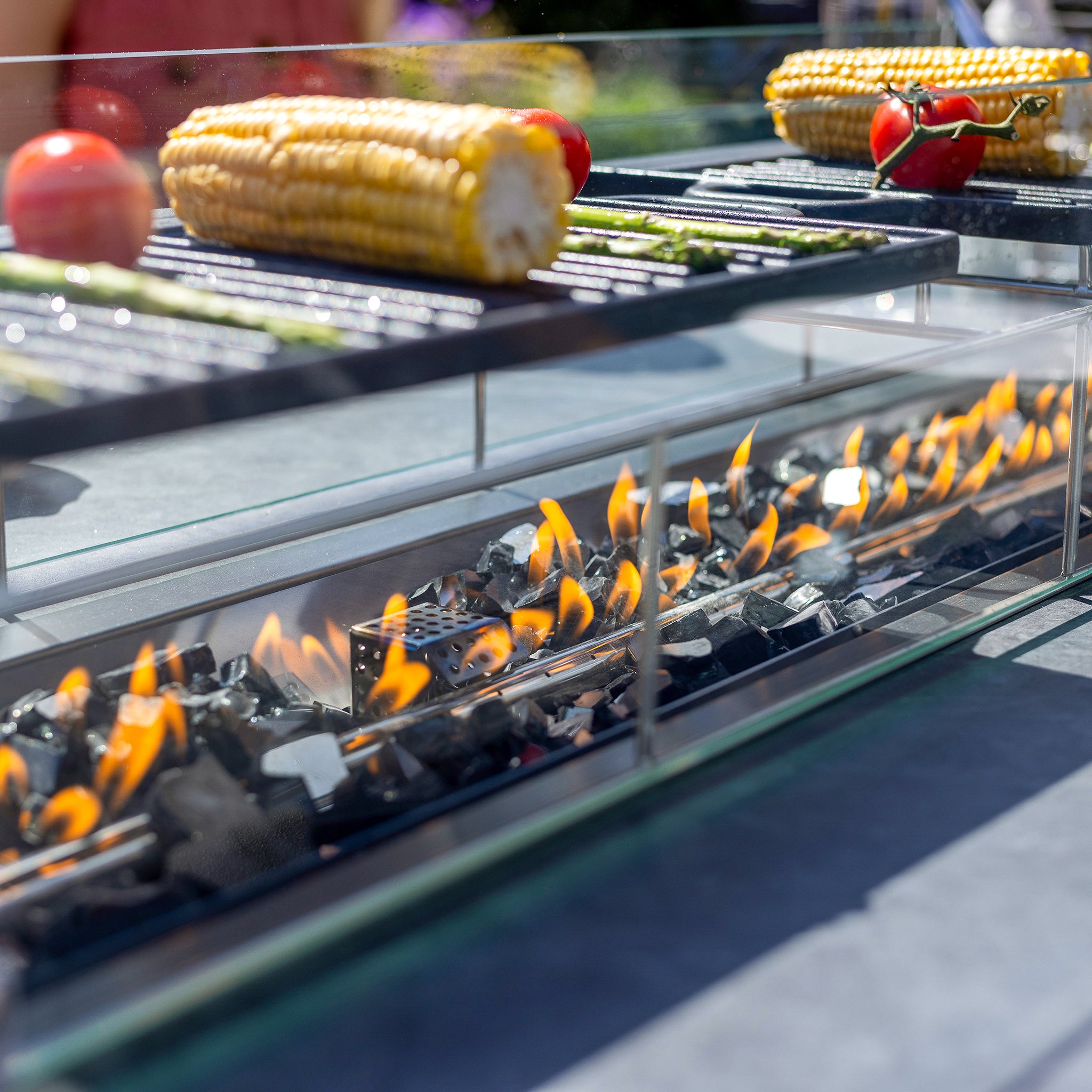 Grill with corn, tomatoes, and peppers roasting over flames and coals, all enhanced by the elegance of the Luna 8 Seat Outdoor Fabric Rectangular Ceramic Firepit Dining Set in Oyster Grey.