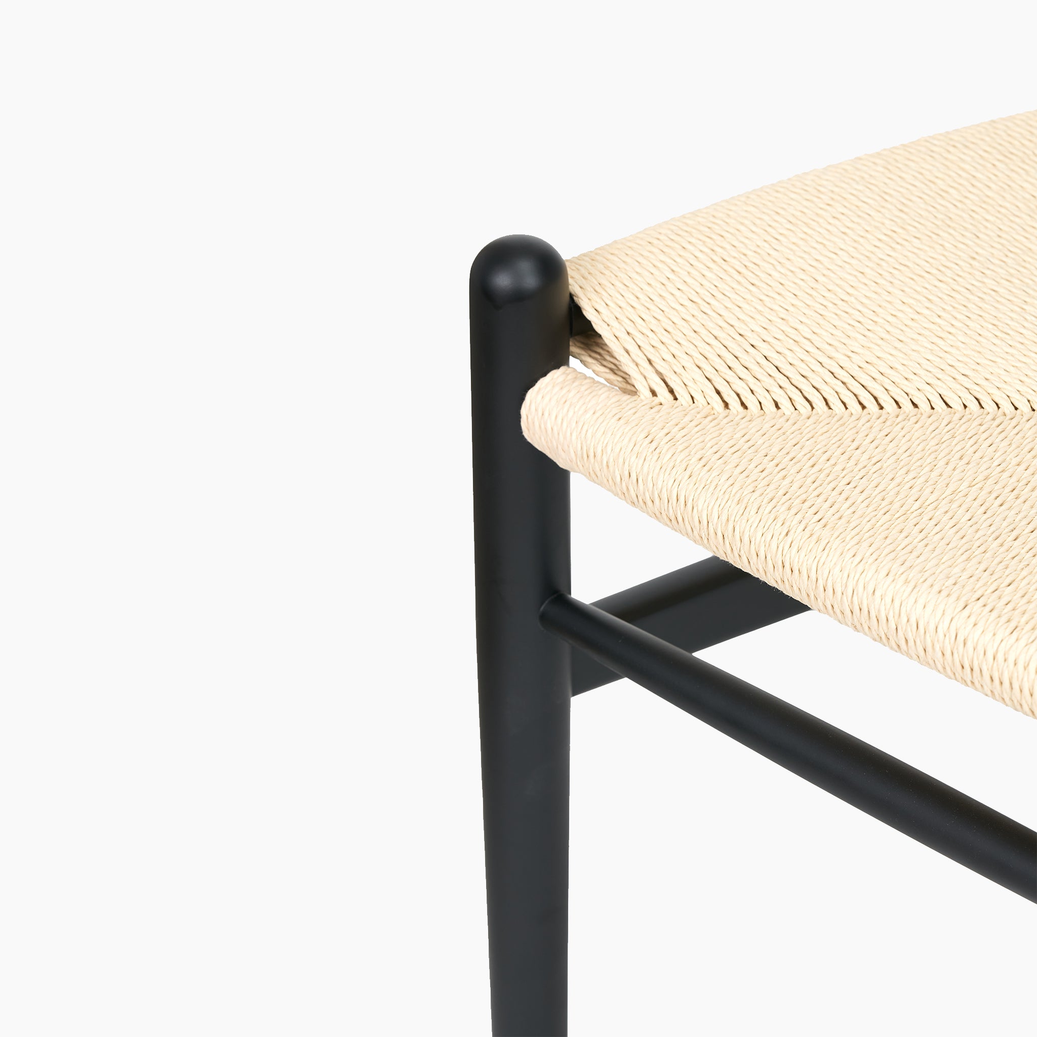 Close-up of the Pacific Lifestyle Quinn Dining Chair with a minimalist look, showcasing a woven natural rope seat and elegant black beech wood frame, highlighting intricate corner details and rich texture.