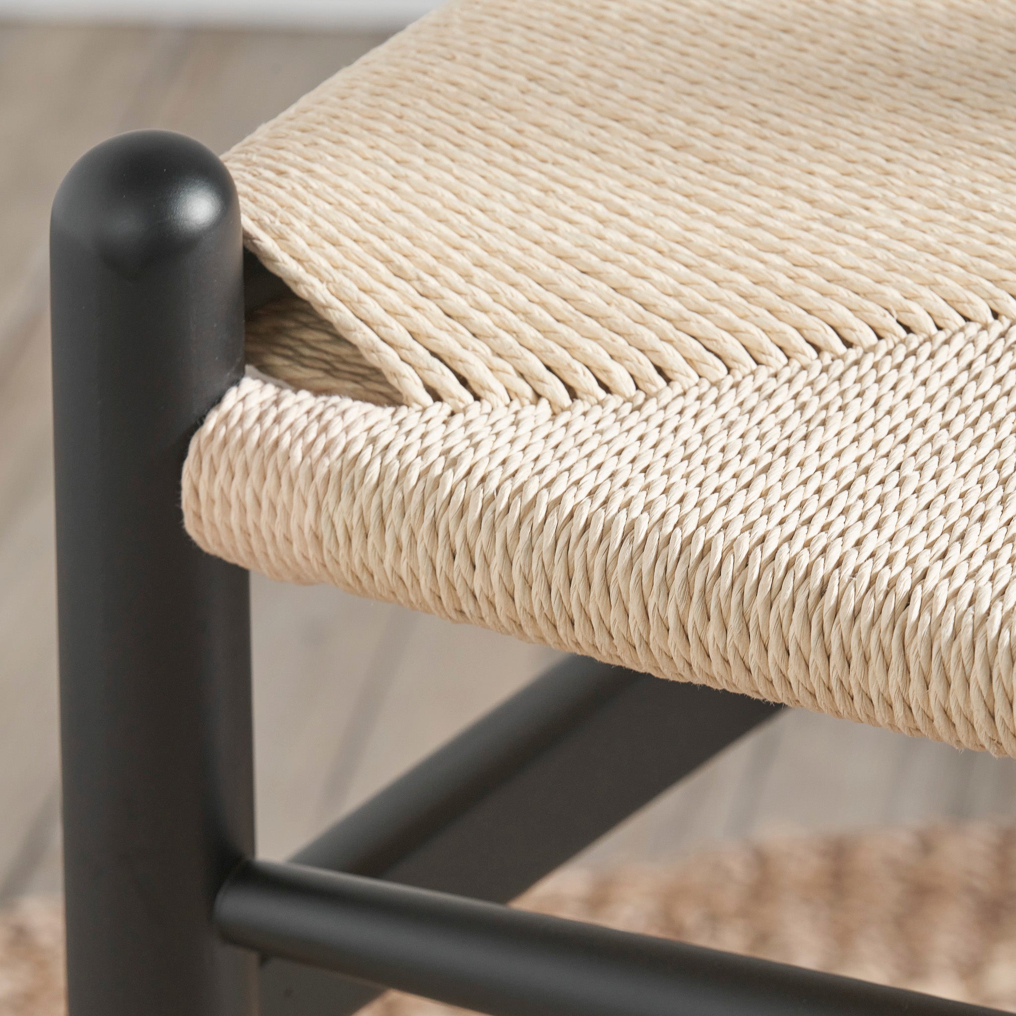 Close-up of a Pacific Lifestyle Quinn Dining Chair with a black beech wood frame and textured natural rope seat, offering rustic charm.
