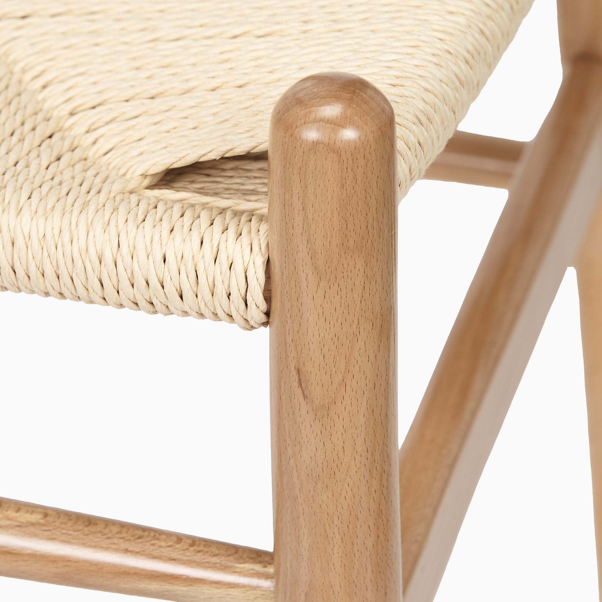Close-up of the Quinn Dining Chair, showcasing a smooth rounded frame crafted from natural beech wood and featuring a seat woven with natural rope.