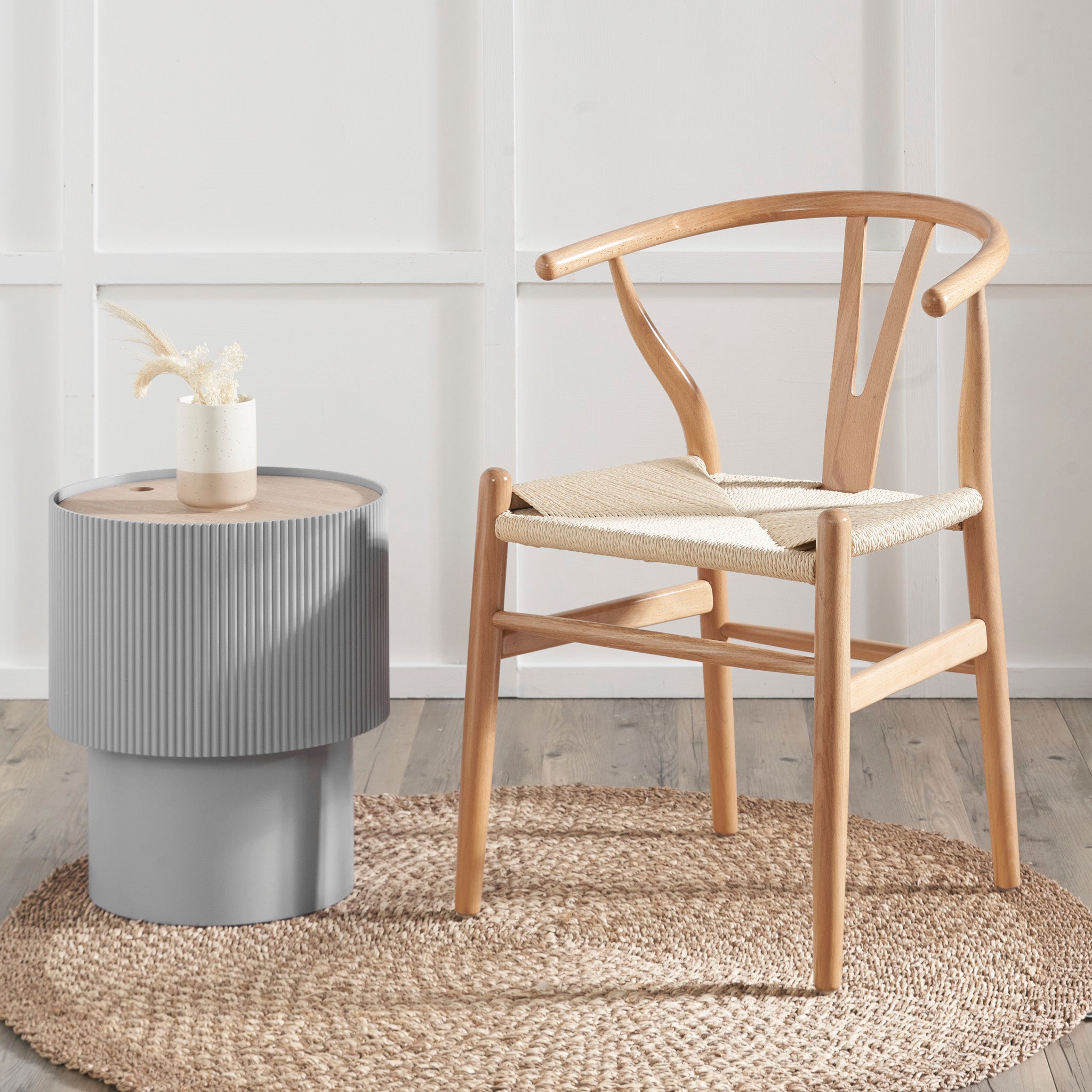 The Pacific Lifestyle - Quinn Natural Beech Wood and Rope Dining Chair pairs elegantly with a gray side table on a woven rug, complemented by minimalist vases and decor in the bright room.