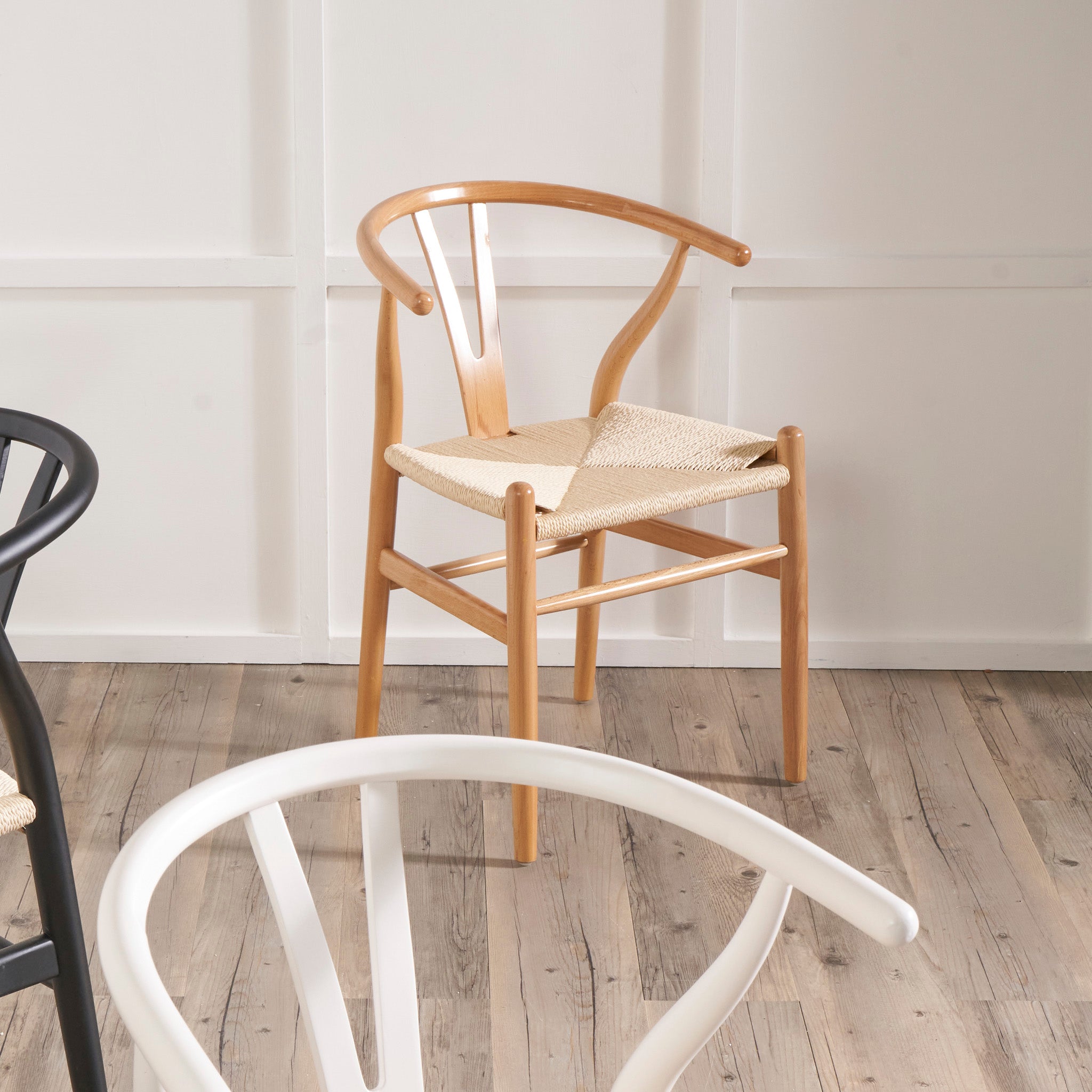 The Pacific Lifestyle - Quinn Dining Chair, made from natural beech wood and featuring a woven natural rope seat, sits elegantly on the wooden floor against the pristine white wall.