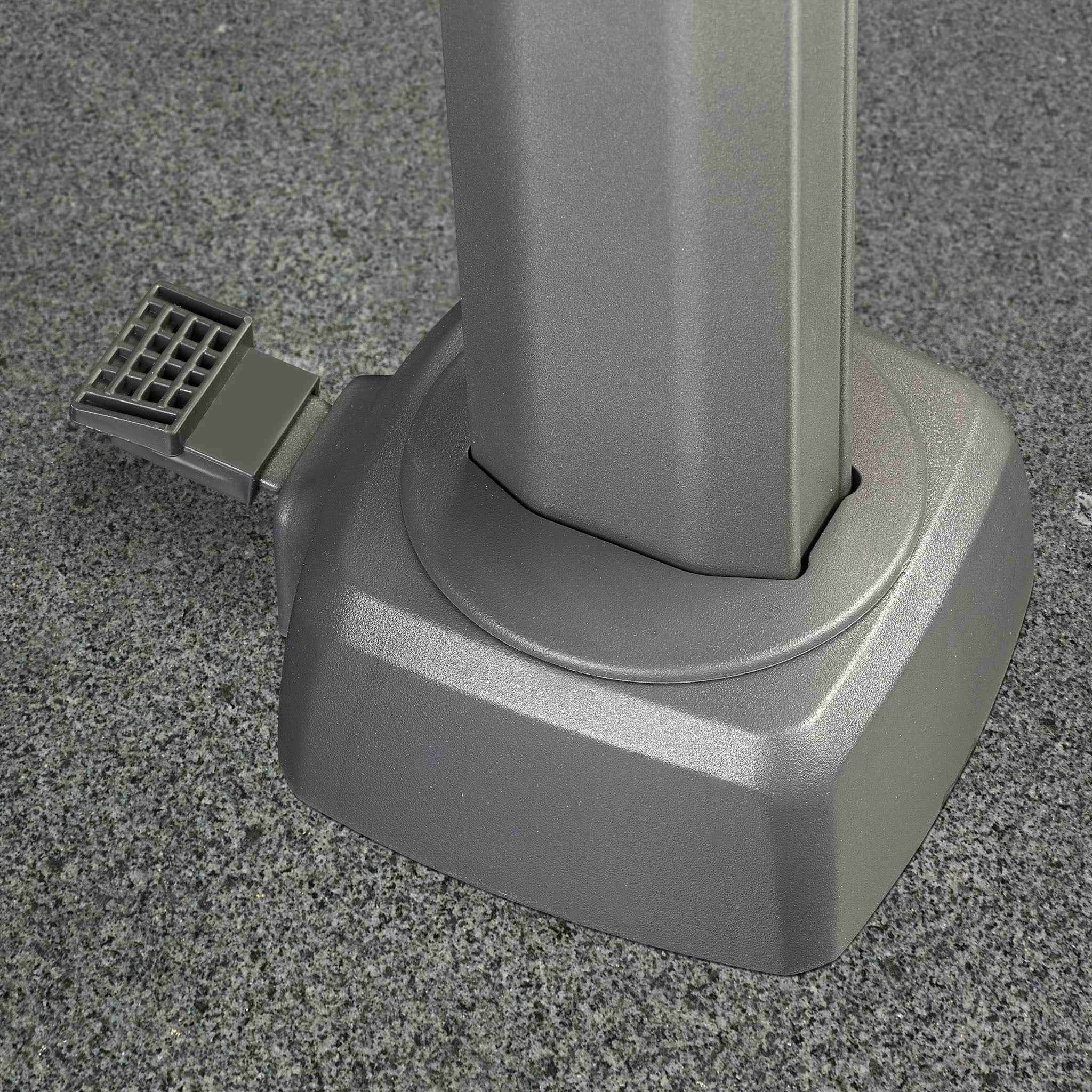 Gray metal pole base with attached foot pedal on a textured gray floor, designed to support the Challenger T2 Premium 3.5m x 2.6m Rectangular Cantilever Parasol in Manhattan Grey.