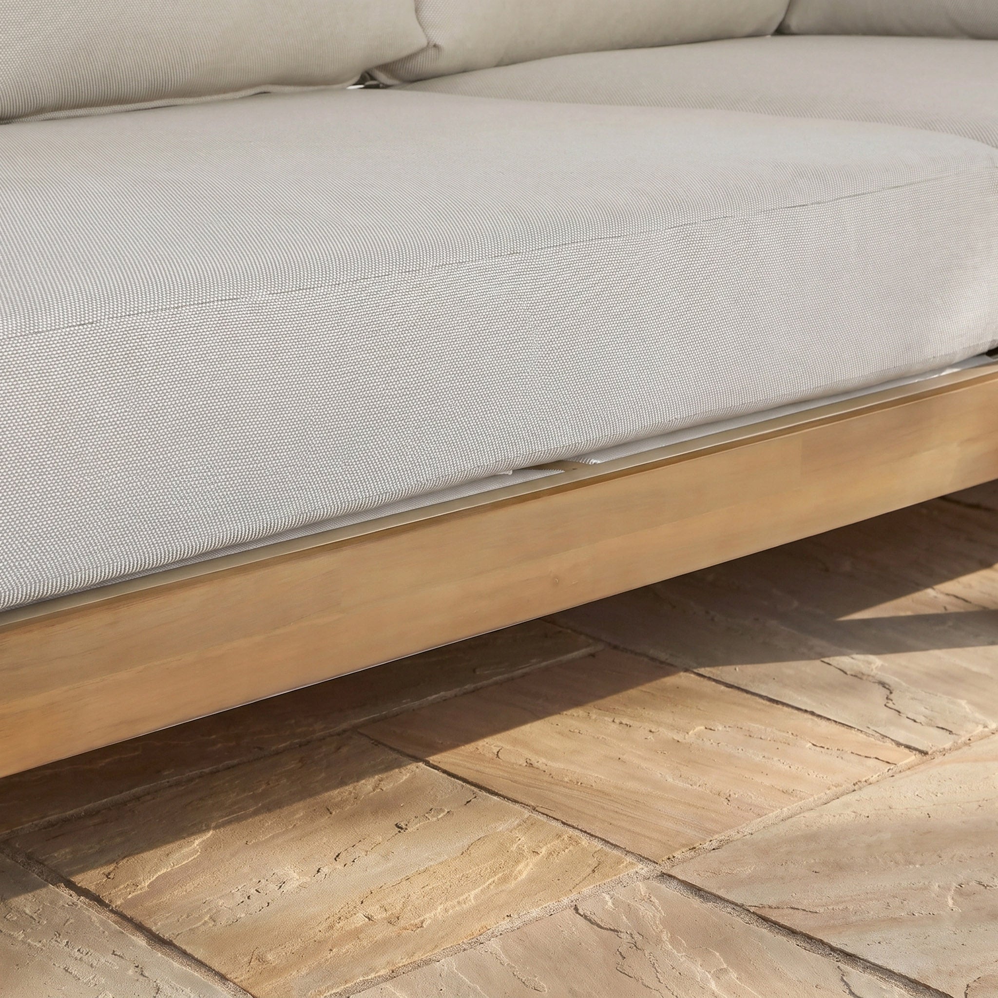 Light beige sofa cushion on a sustainable acacia wood frame from the Ava Corner Sofa Set in Latte, shown on tan tiled flooring in a close-up view.