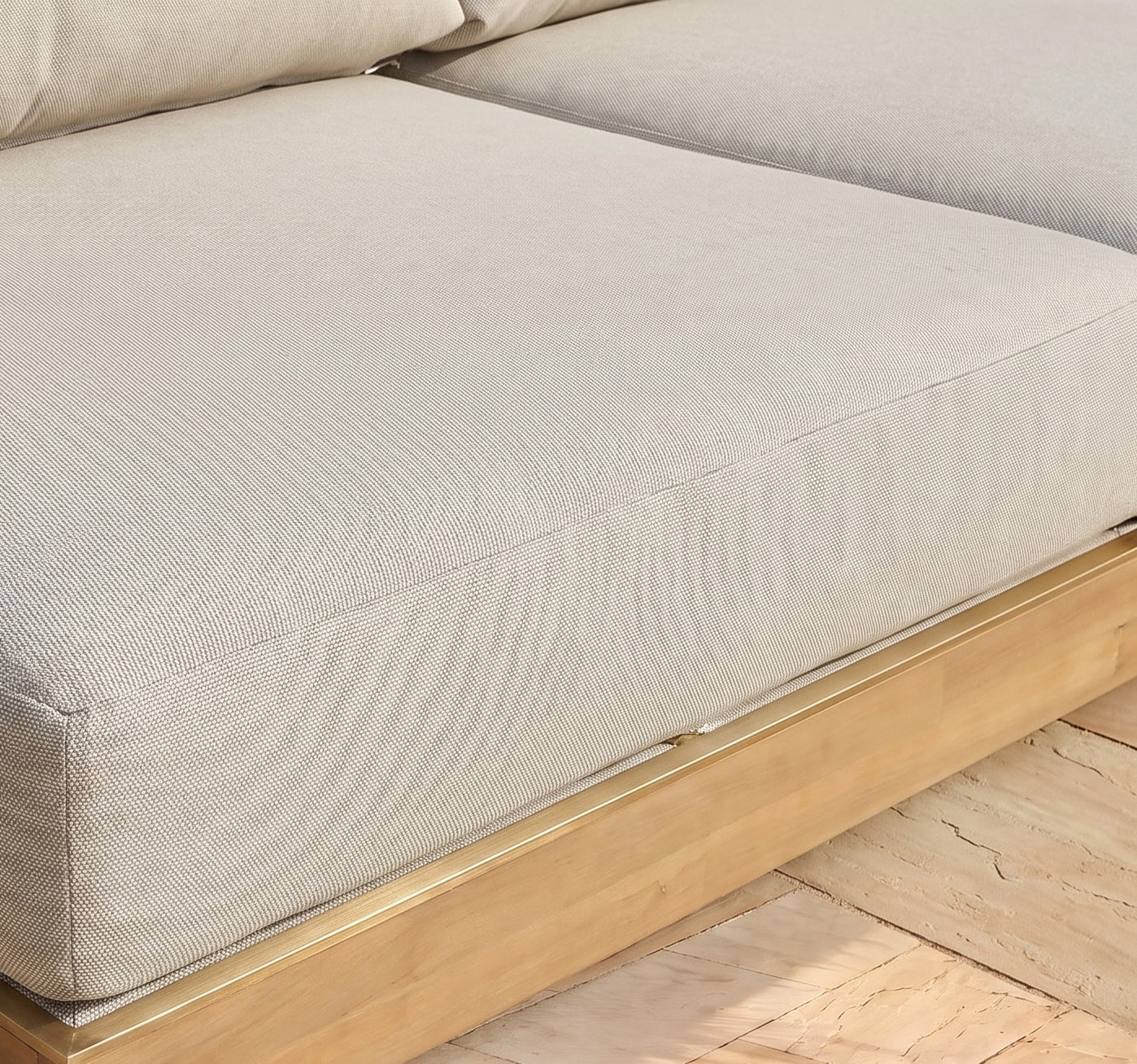 Close-up of the Ava Corner Sofa Set in Latte, featuring a beige upholstered cushion and an elegant wooden base crafted from sustainable acacia wood, resting on a light wood floor.