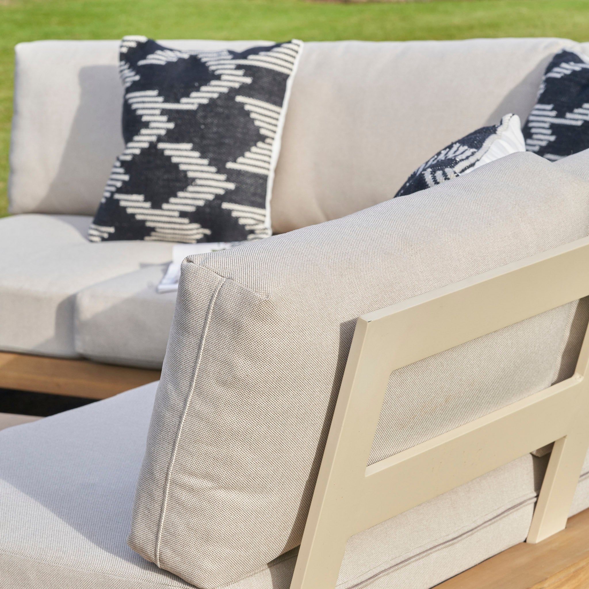 The Pacific Lifestyle - Osaka Corner Sofa Set in Latte boasts a beige finish with black and white pillows, crafted from sustainable acacia wood—an elegant and timeless outdoor furniture choice.