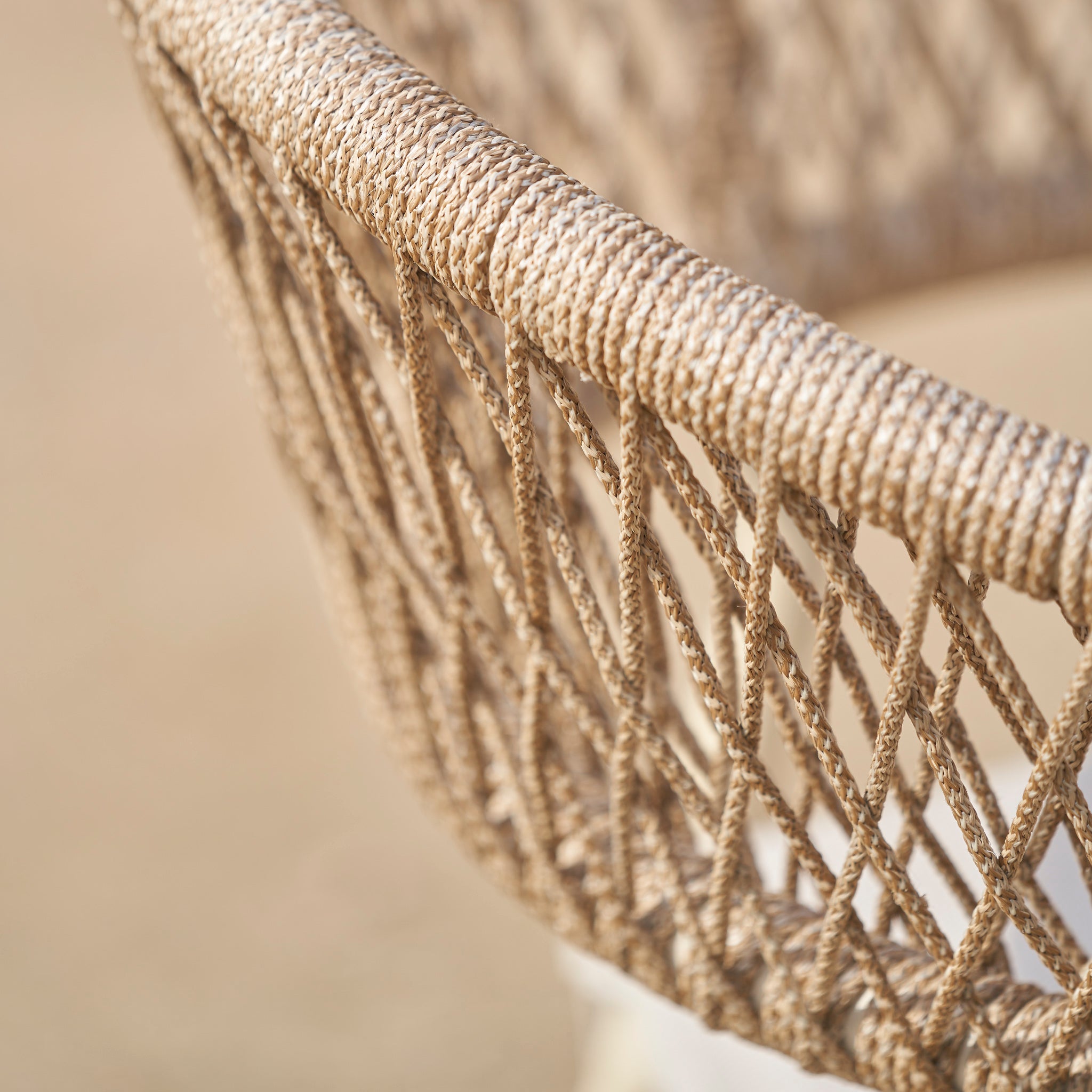 Close-up of a woven rope chair with a crisscross pattern from the Pacific Lifestyle - Osaka 6 Seat Dining Set in Latte, set against a blurred neutral background.