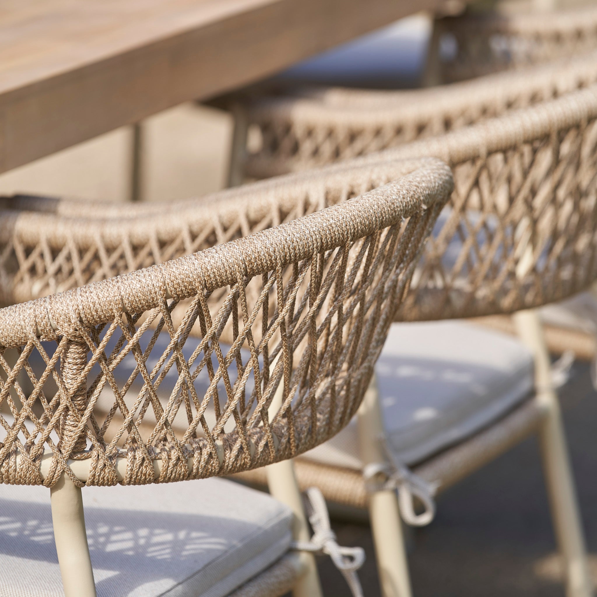 Close-up of woven rattan chairs with cushions around the Pacific Lifestyle - Osaka 6 Seat Dining Set in Latte, perfect for stylish outdoor dining.