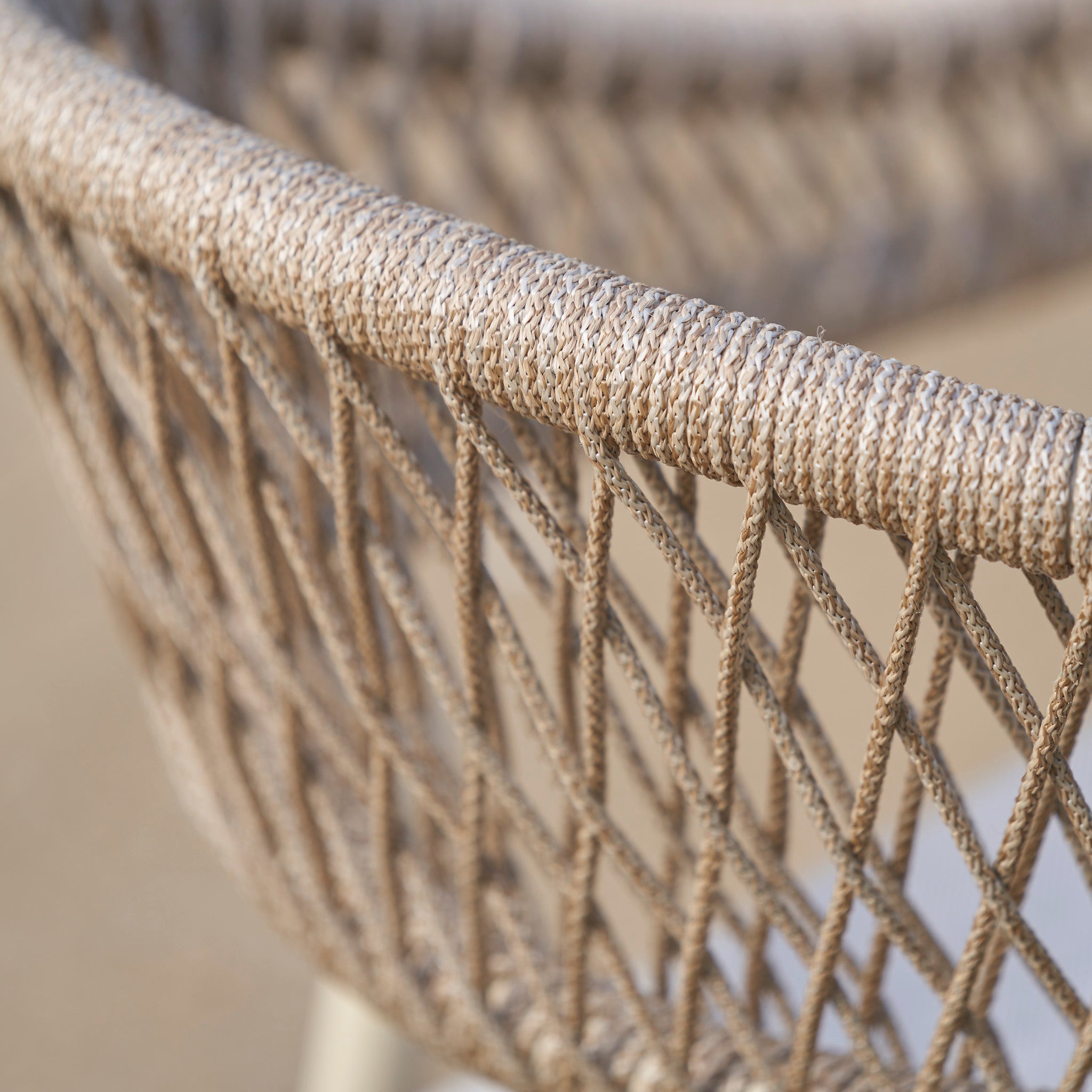 Close-up of a woven rope chair backrest with a crisscross pattern in natural beige tones, part of the Pacific Lifestyle - Osaka 6 Seat Dining Set in Latte, featuring an Acacia wood dining table and stylish outdoor furniture.