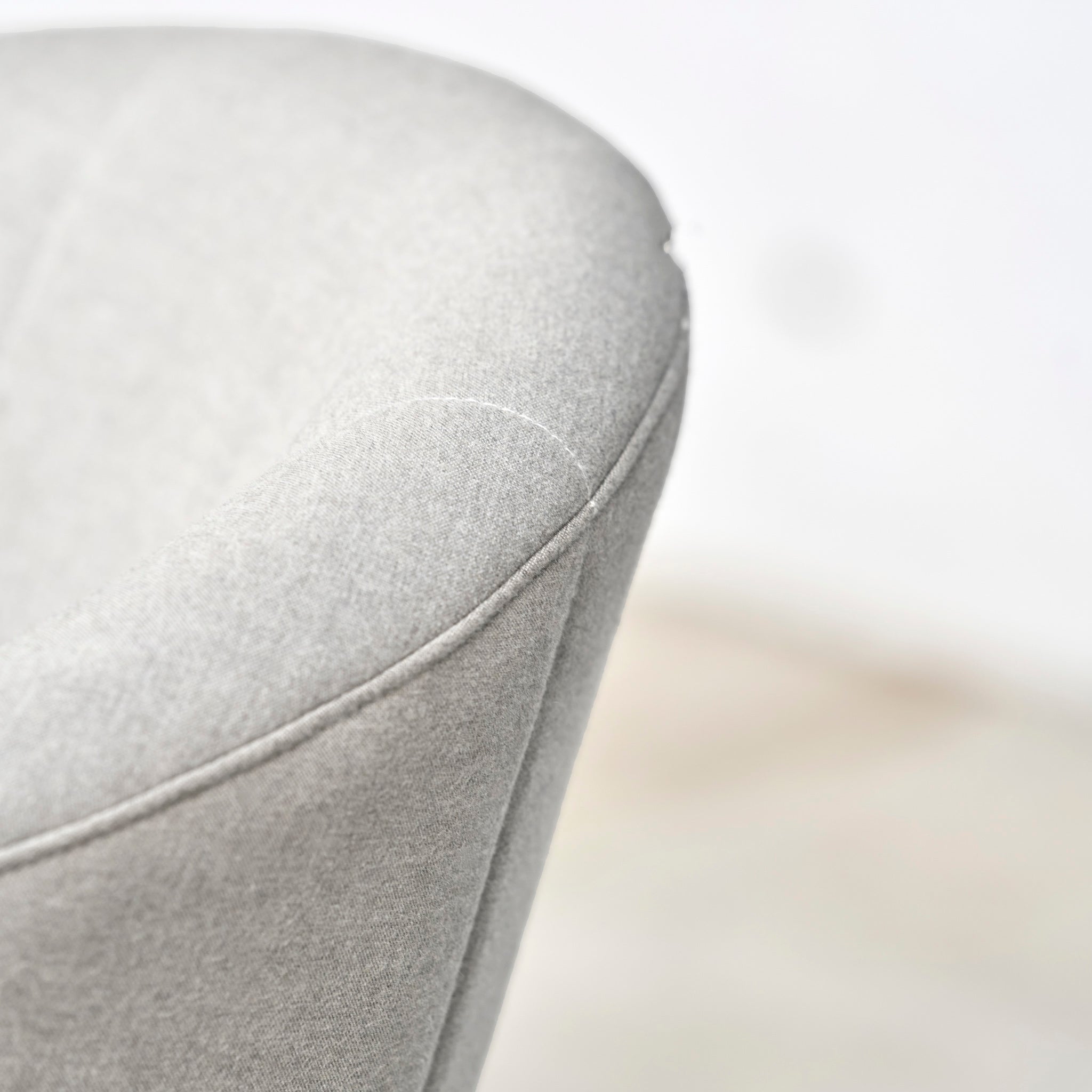 Close-up of a light gray upholstered chair from the Kai 4 Seat Round Dining Set in Light Grey, showcasing its soft fabric and gently curved backrest against a blurred background—an elegant choice for any small patio dining set or light grey garden furniture arrangement.