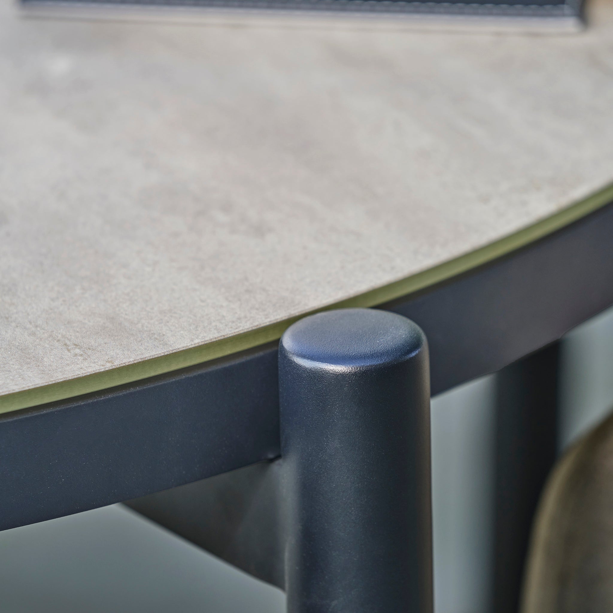 Close-up of the Kai 4 Seat Round Dining Set in Light Grey, highlighting its smooth, light grey garden furniture surface and dark metal leg.