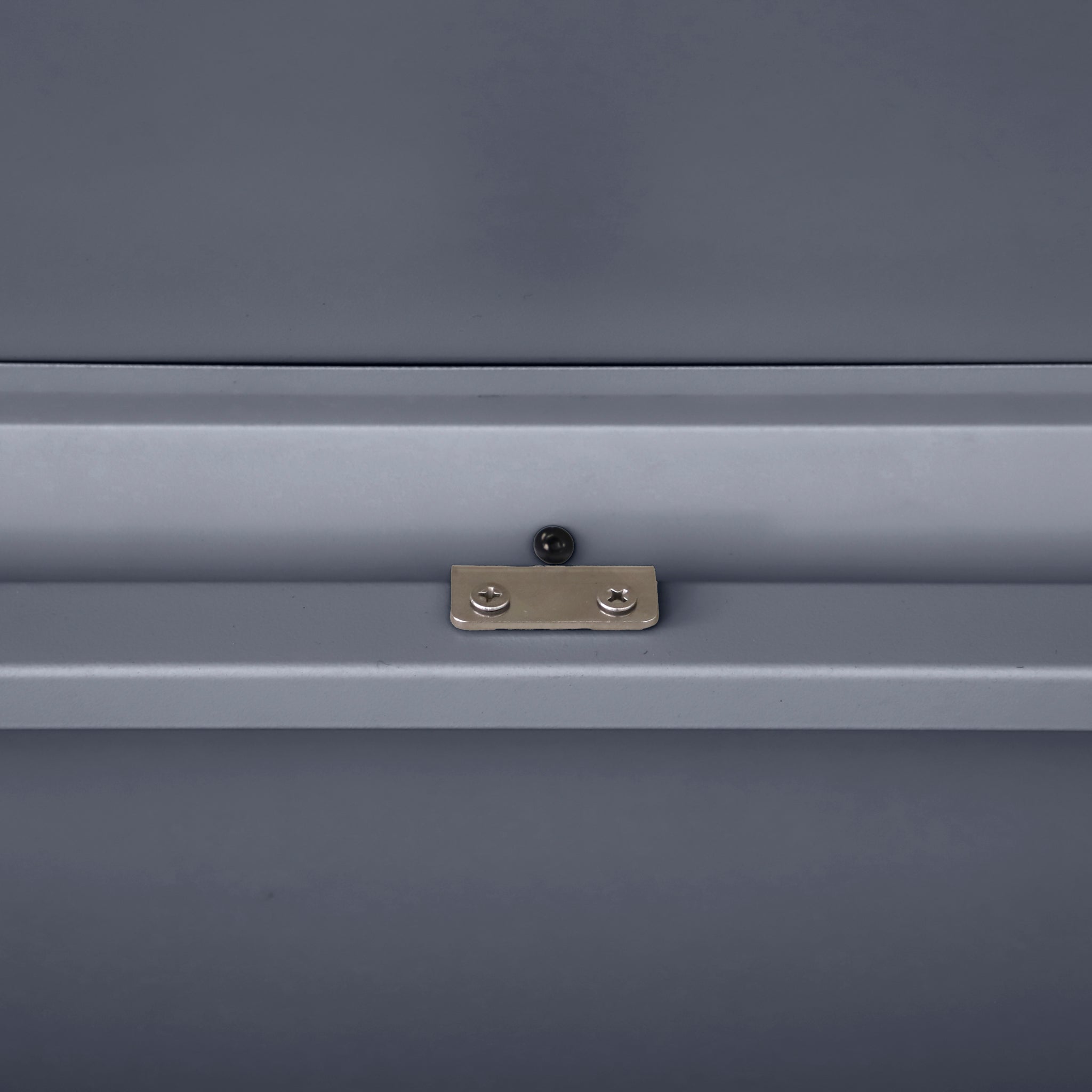 Close-up of a metal latch with two screws on a smooth gray surface, perfect for securing the Pacific Lifestyle - Rhode Island Large Outdoor Cushion Box in Anthracite.