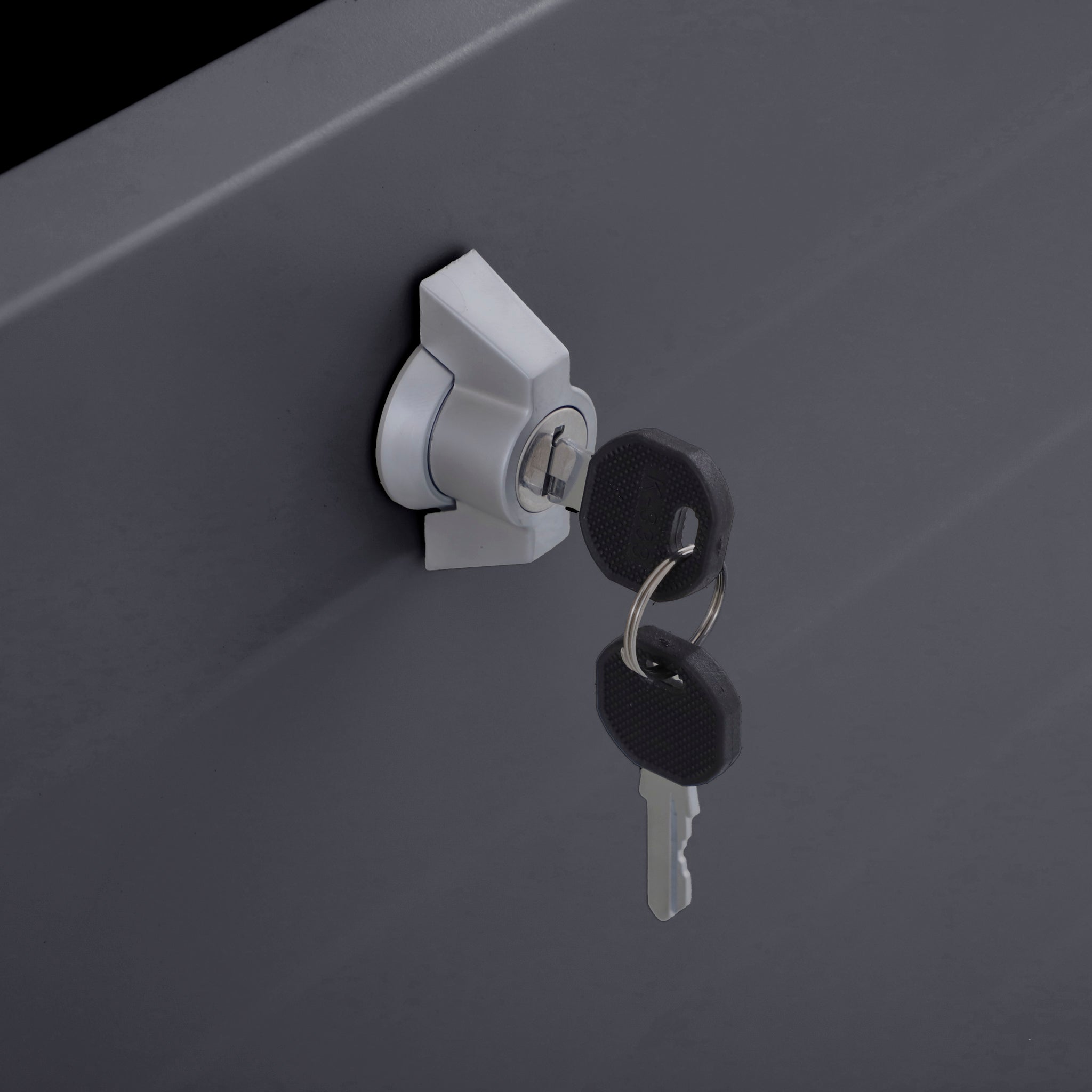 A close-up of two keys in the lock of the Pacific Lifestyle - Rhode Island Small Outdoor Cushion Box in Anthracite highlights its robust galvanised steel build and sleek anthracite finish.