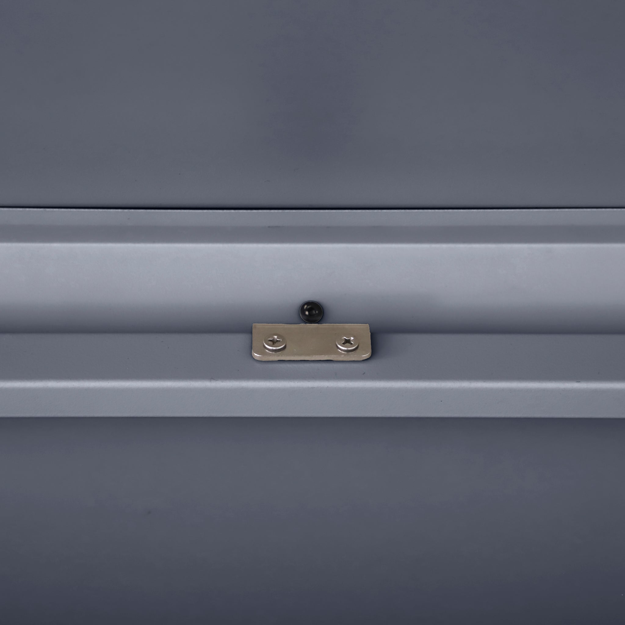 A close-up of the Pacific Lifestyle - Rhode Island Small Outdoor Cushion Box in anthracite, highlighting the metal surface with a small brass plate and centered screw.