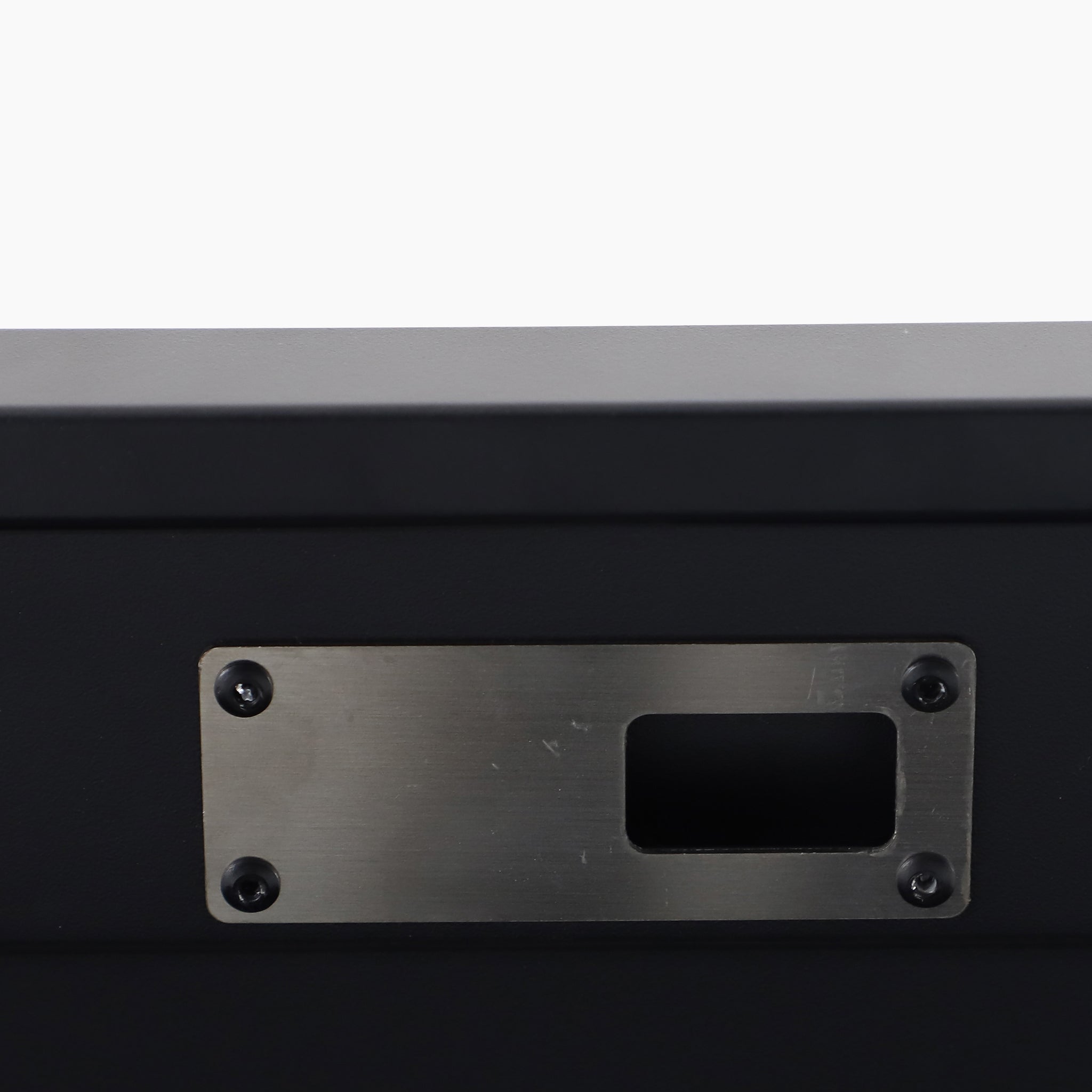 Close-up of the Pacific Lifestyle - Rhode Island Large Outdoor Cushion Box in Black, featuring a steel body with a rectangular silver plate, open slot, and four screws—ideal for stylish outdoor storage.