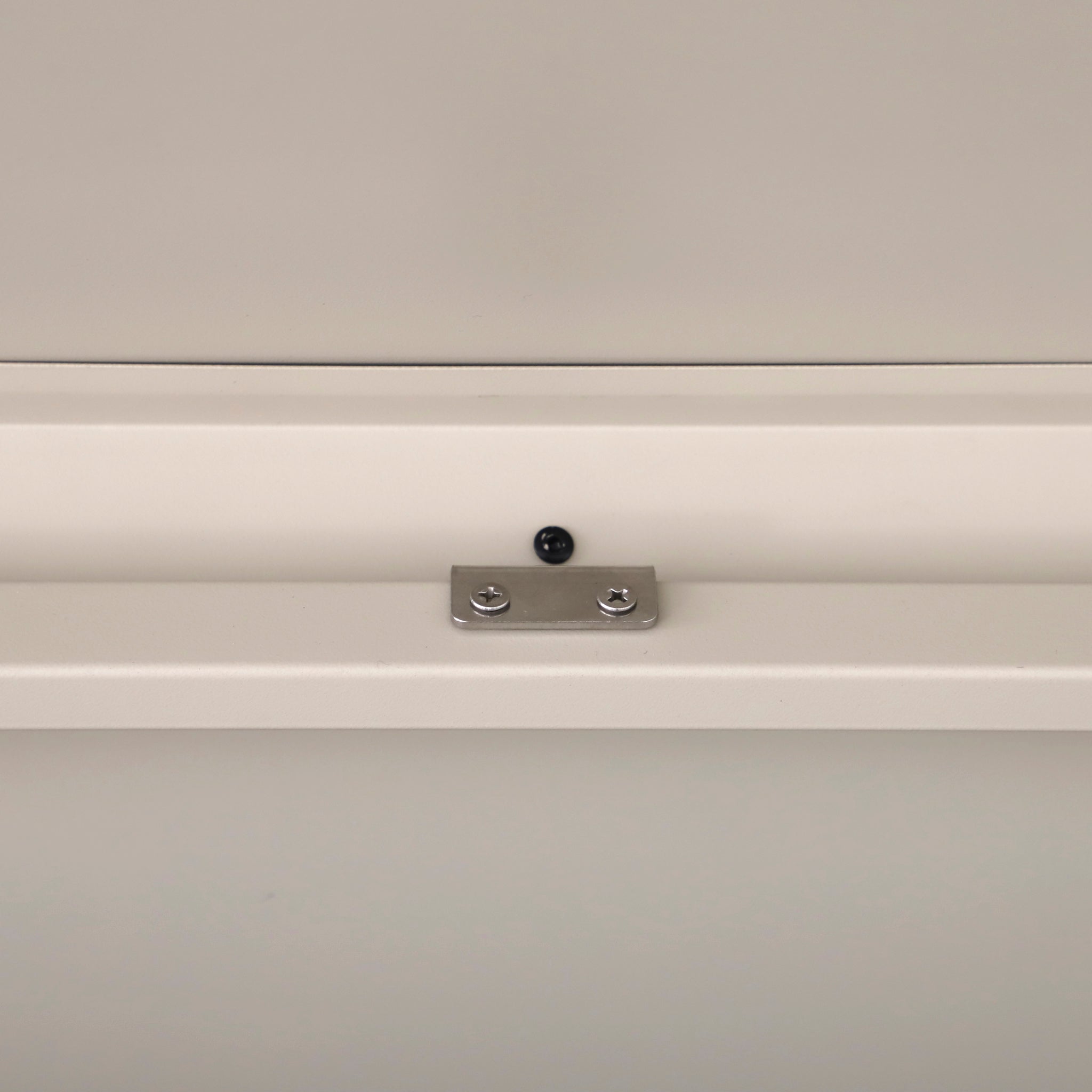Close-up of a metal bracket with two screws mounted on a light wall, similar to the sturdy fittings found in the Pacific Lifestyle Rhode Island Large Outdoor Cushion Box in Pebble.