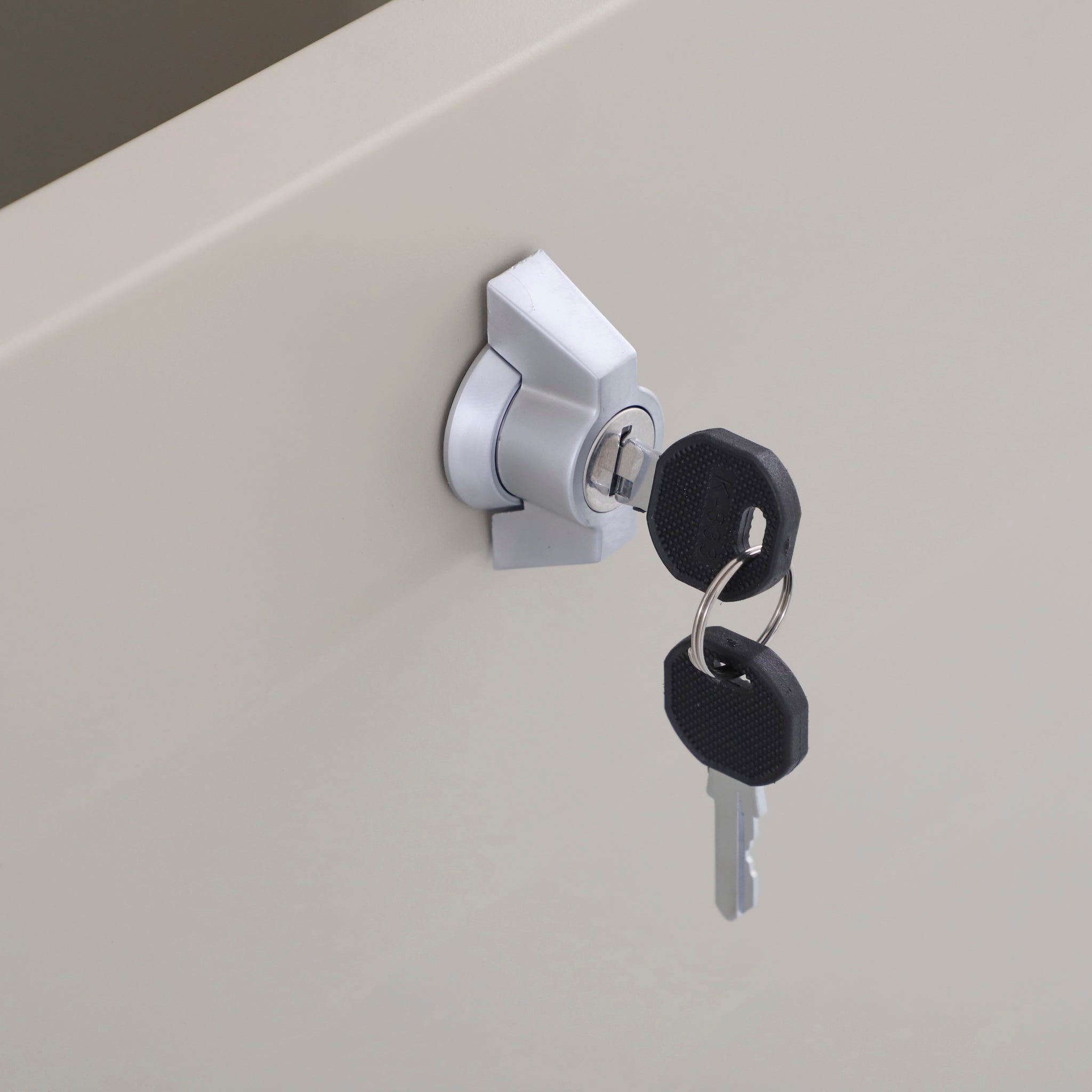 Close-up of a metal lock with two black keys inserted on a light surface—perfect for securing the Pacific Lifestyle - Rhode Island Large Outdoor Cushion Box in Pebble, crafted from durable galvanised steel.