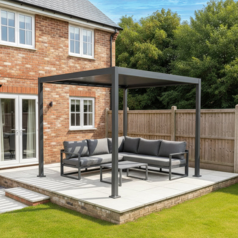 Modern patio with a PergoSTET Lite 2.4m x 3m Metal Rectangular Pergola in Grey featuring tilting louvres for shade, plus an outdoor sofa and table on tiles beside a brick house and lawn.