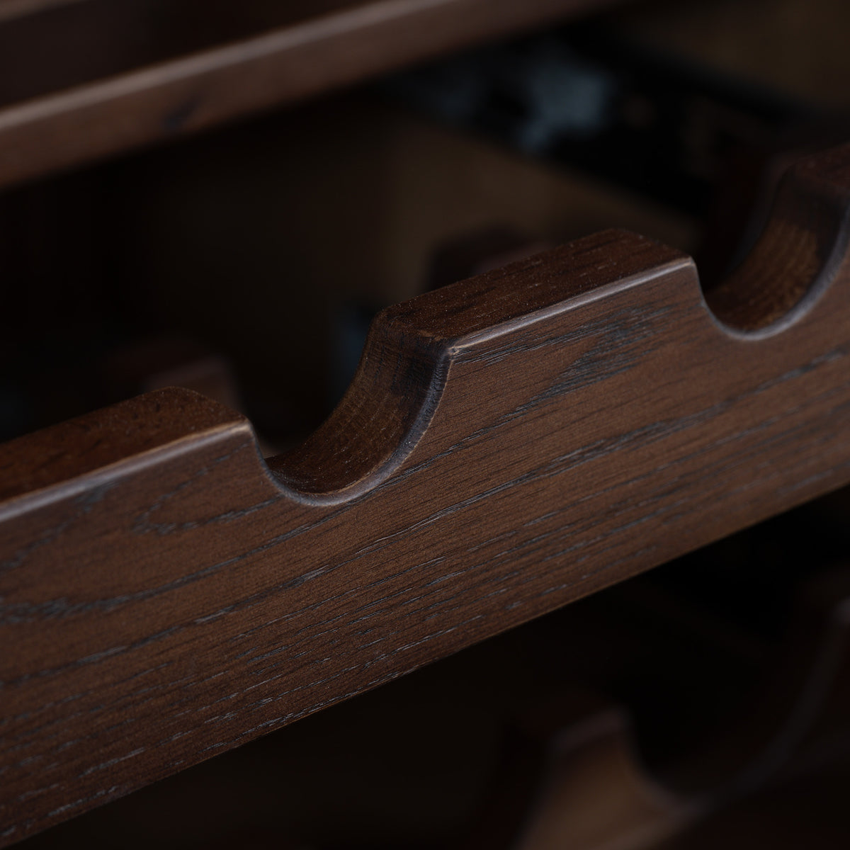 Close-up of the dark walnut Oslo Grand 4 Door Sideboard with Wine Rack, highlighting the gracefully curved slots designed to hold wine bottles. This elegant detail exemplifies the sophisticated craftsmanship characteristic of this finely made piece.