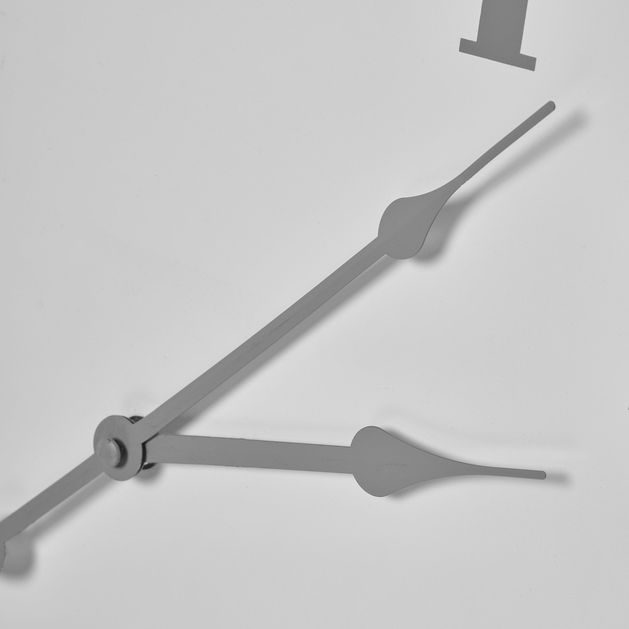 Close-up of the Aubrey Wall Clock, showcasing its minimalist gray hour and minute hands set against a pristine white face, all encased in a sleek silver-effect metal frame.