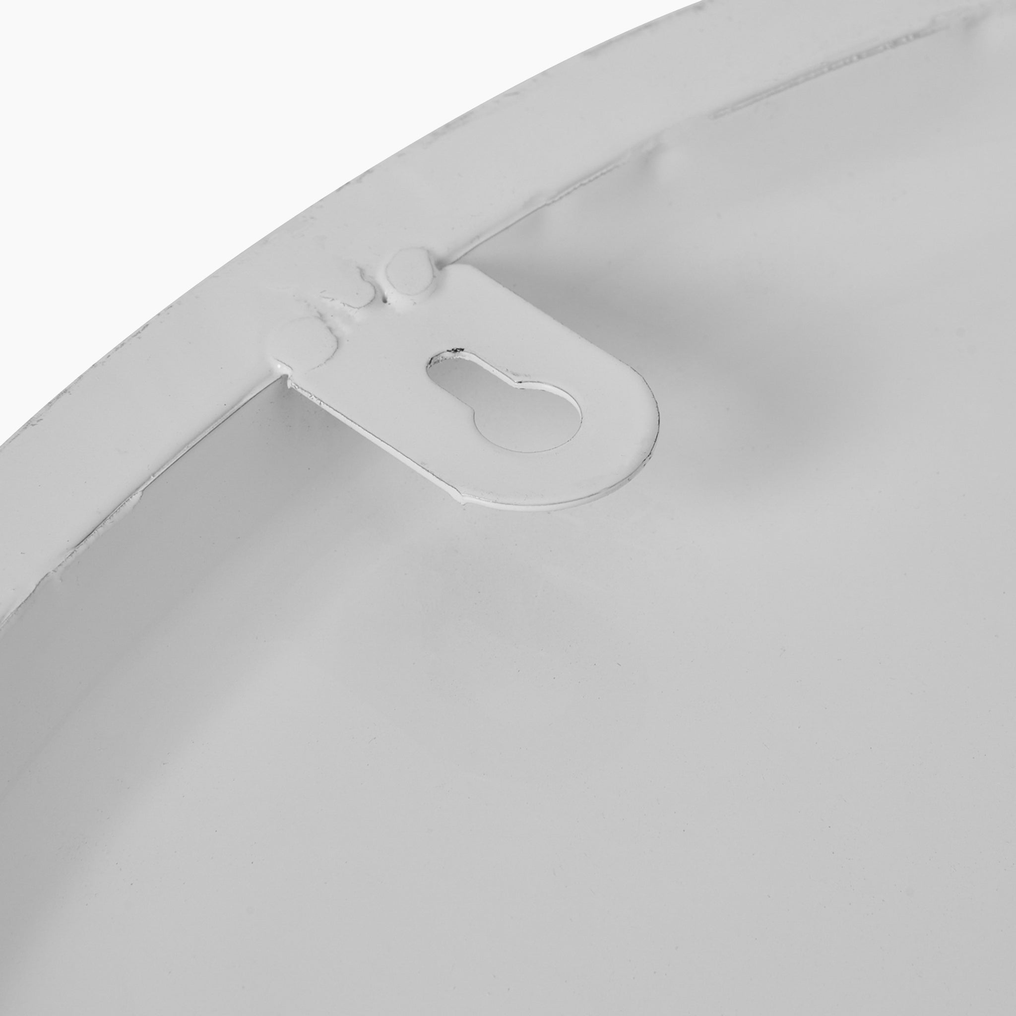 Close-up view of a white metal disc featuring a small bracket near the edge, reminiscent of the sleek design characteristic of an Aubrey Wall Clock.