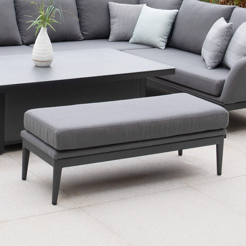 A Luna Bench in Grey with plush cushions sits beside a matching outdoor sectional and table, creating inviting seating on the tiled patio.