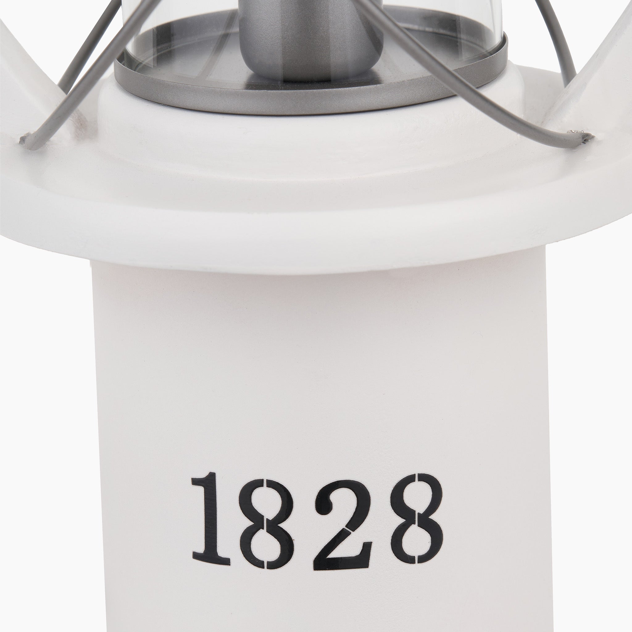 Close-up of the Pacific Lifestyle Gibson Wood Lantern Table Lamp in White Wood, featuring a black "1828" and a metal-framed glass top.