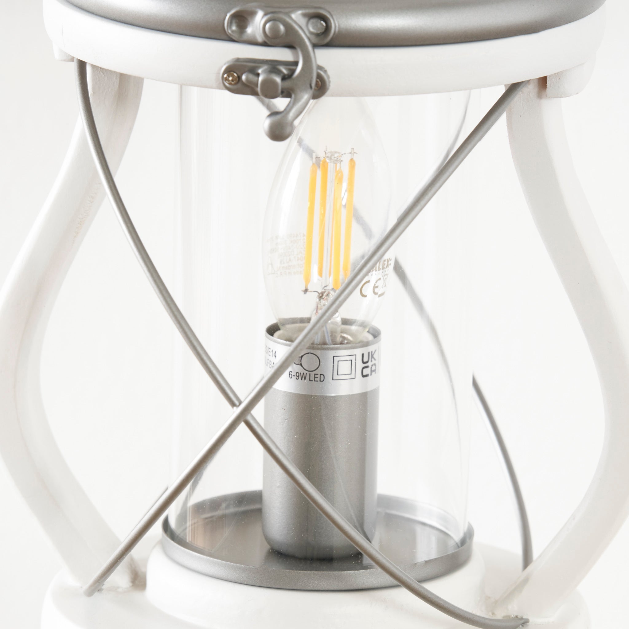 Close-up of the Pacific Lifestyle - Gibson Wood Lantern Table Lamp in White Wood, featuring a clear glass bulb and metallic accents inspired by Victorian lanterns.