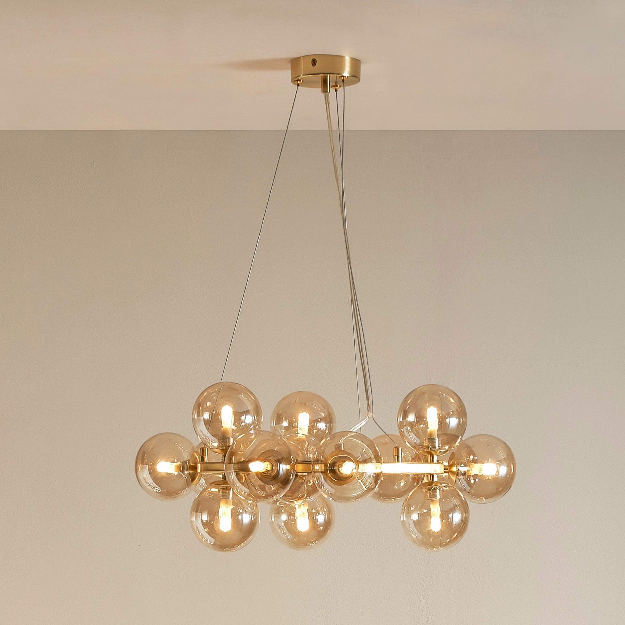 The Pacific Lifestyle Vecchio chandelier is a statement light source with eight lustre glass pendant bulbs and a gold finish, elegantly suspended by wires from the ceiling.