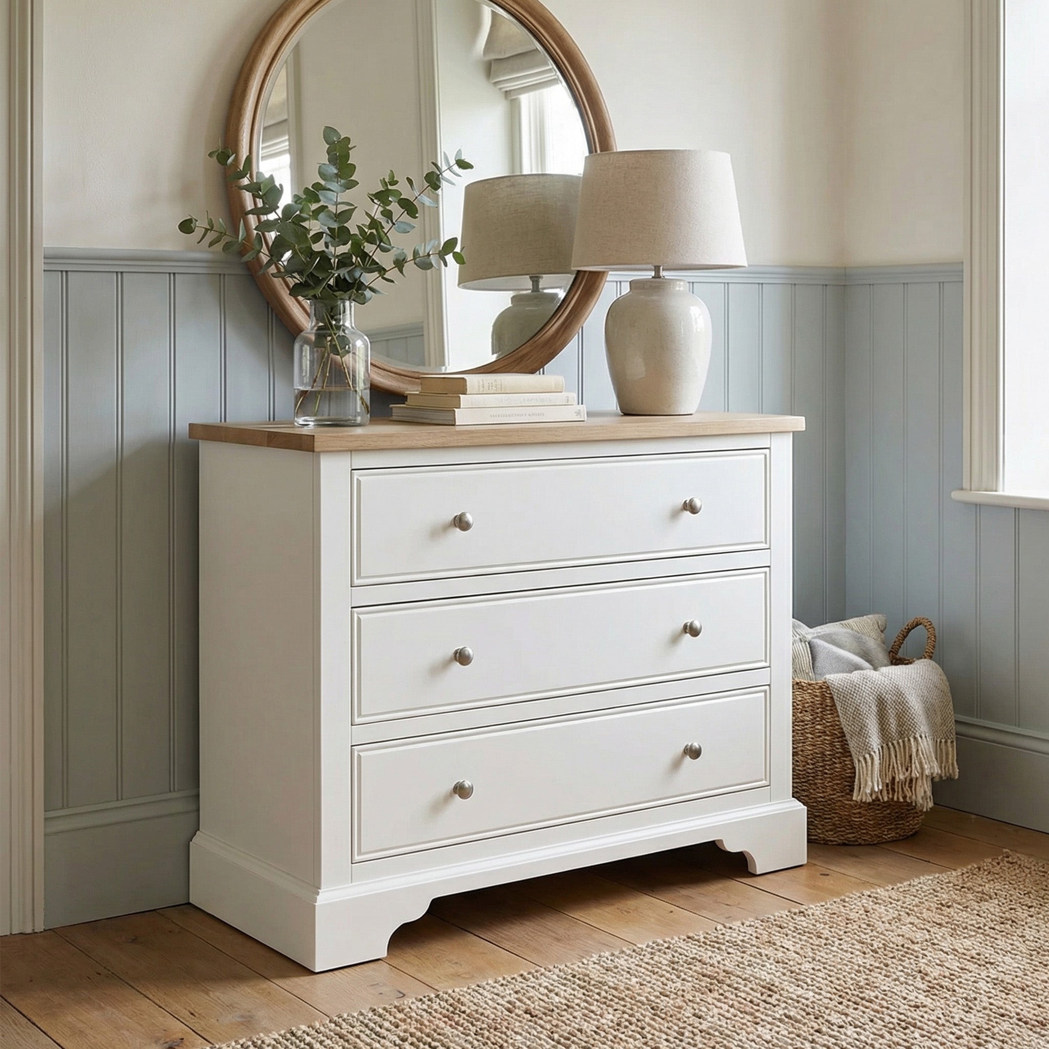 Amberley 3 Chest of Drawers in Warm White comes with a round mirror, lamp, book, decorative greenery, and a woven basket—ideal for stylish and space-saving bedroom storage.