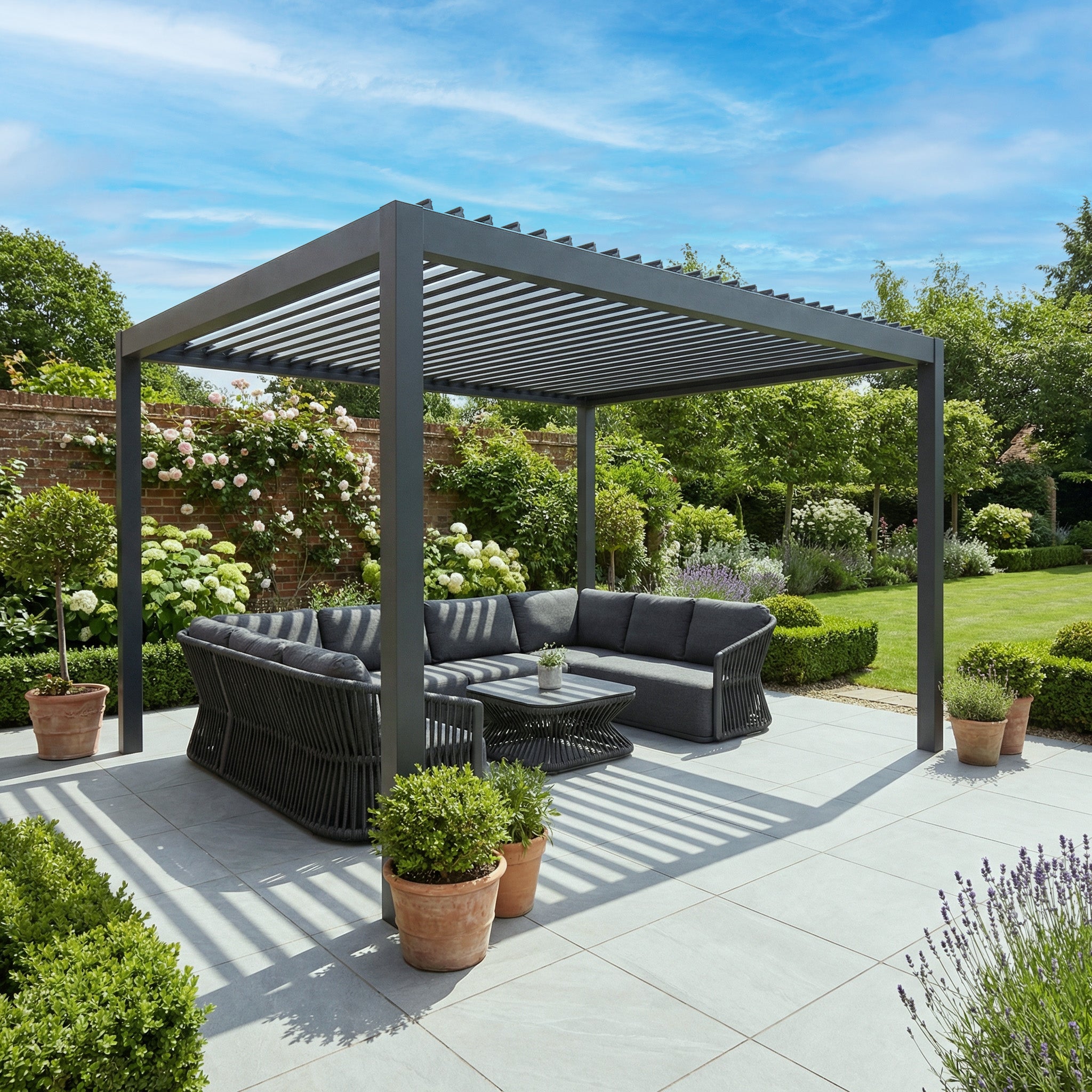 PergoSTET Deluxe 3m x 4m rectangular pergola with motorised LED louvres in grey frames a stylish outdoor area with dark seating, potted plants, and a lush green garden.