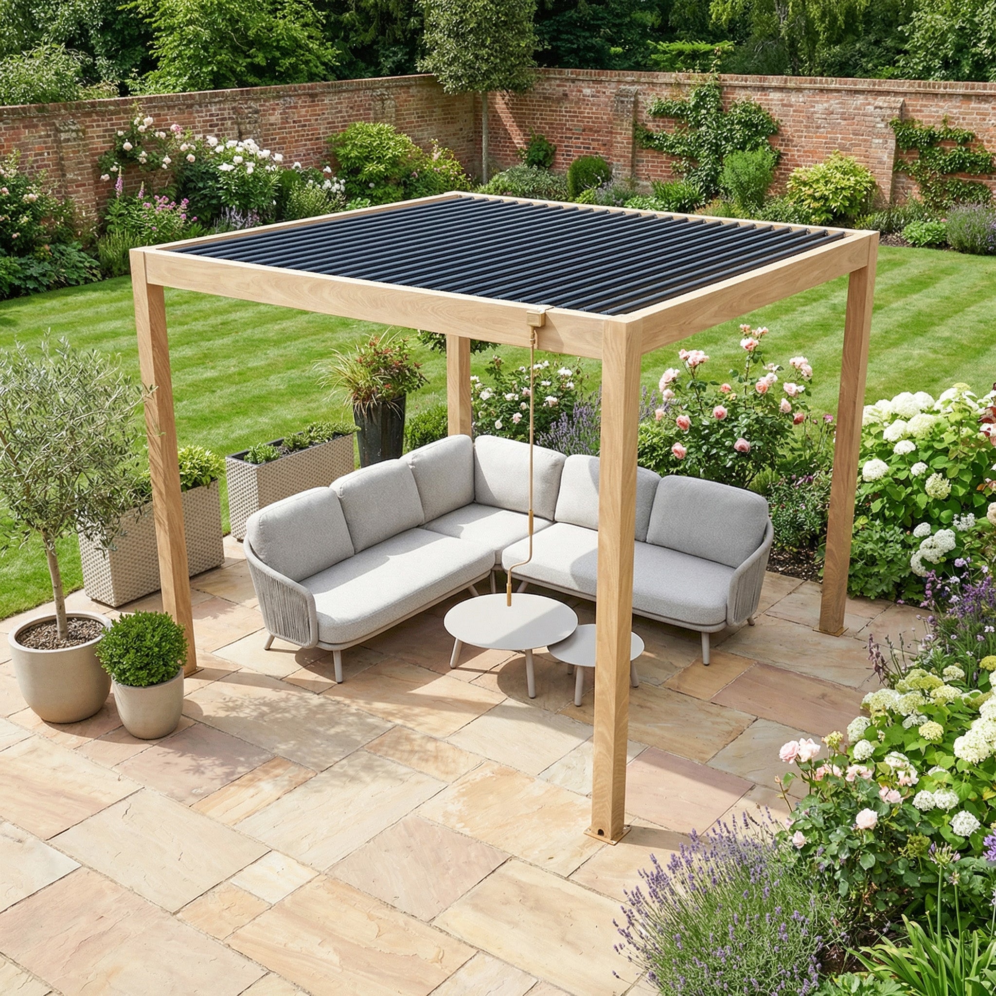 The PergoSTET Plus 3m x 3m Square Pergola with LED lighting in Wood Effect shelters a gray outdoor sofa set and tables on a landscaped garden patio.