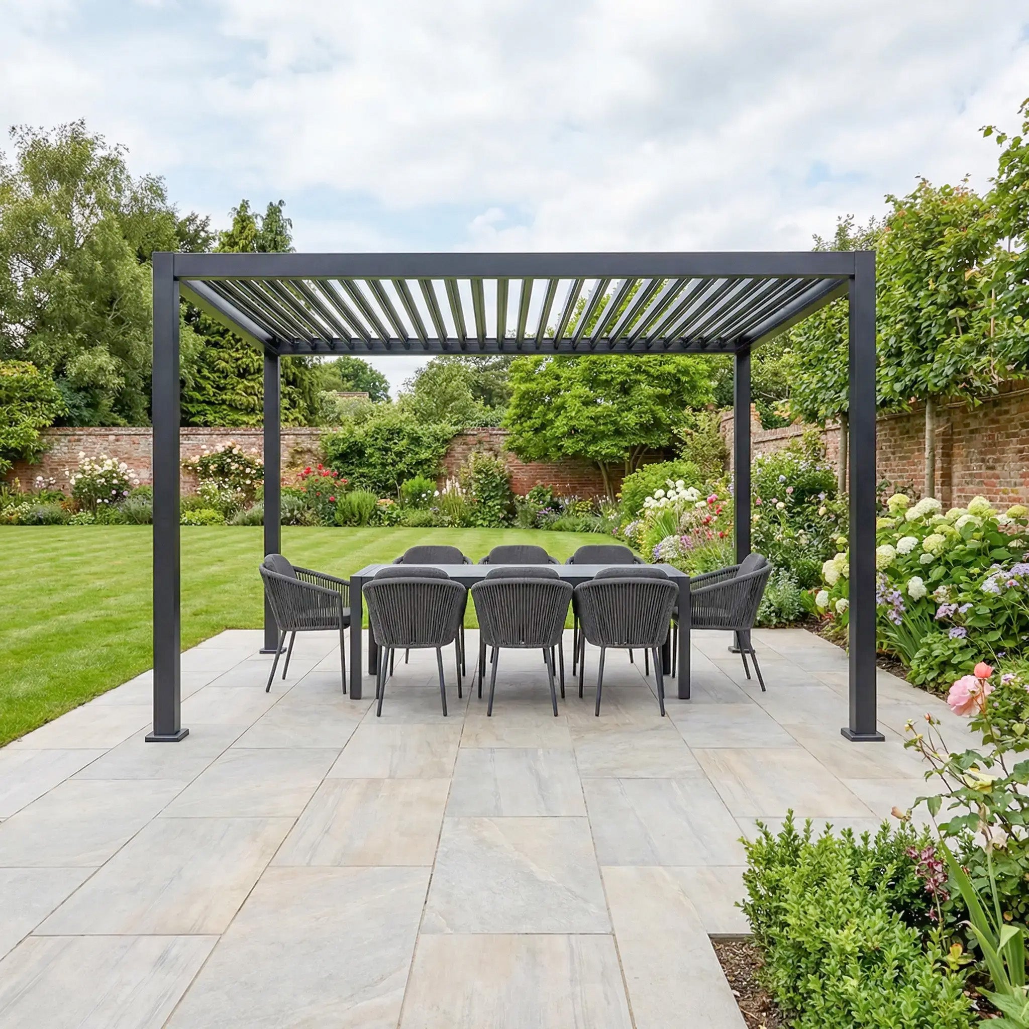 Modern outdoor dining area with the PergoSTET Lite Neo 3m x 4m Grey Metal Pergola, featuring a louvred roof, built-in drainage system, chairs, and table on the patio, surrounded by a lush garden.