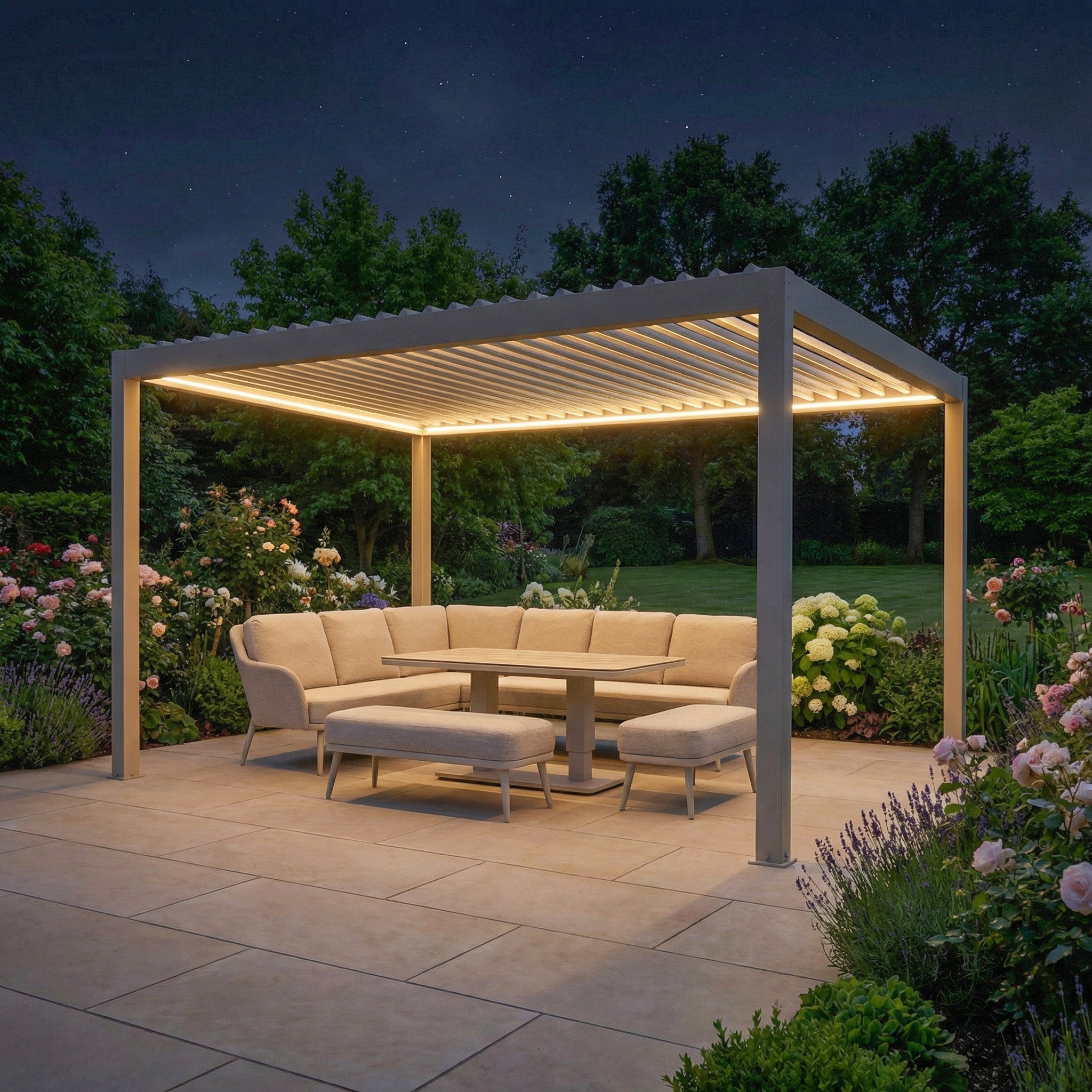 A modern outdoor seating area under the PergoSTET Plus Frame Only 3m x 4m Rectangular Pergola in Latte with LED lighting, surrounded by flowers and greenery at night. Features a sleek design and built-in drainage system for stylish, functional outdoor living.