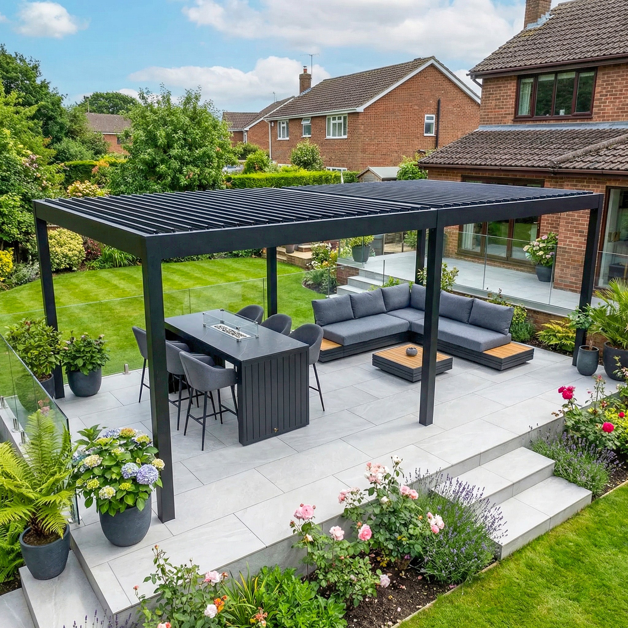The patio features a manicured garden, outdoor dining set, sectional sofa, and a PergoSTET Deluxe 3m x 6m rectangular pergola with motorised LED louvres in grey.