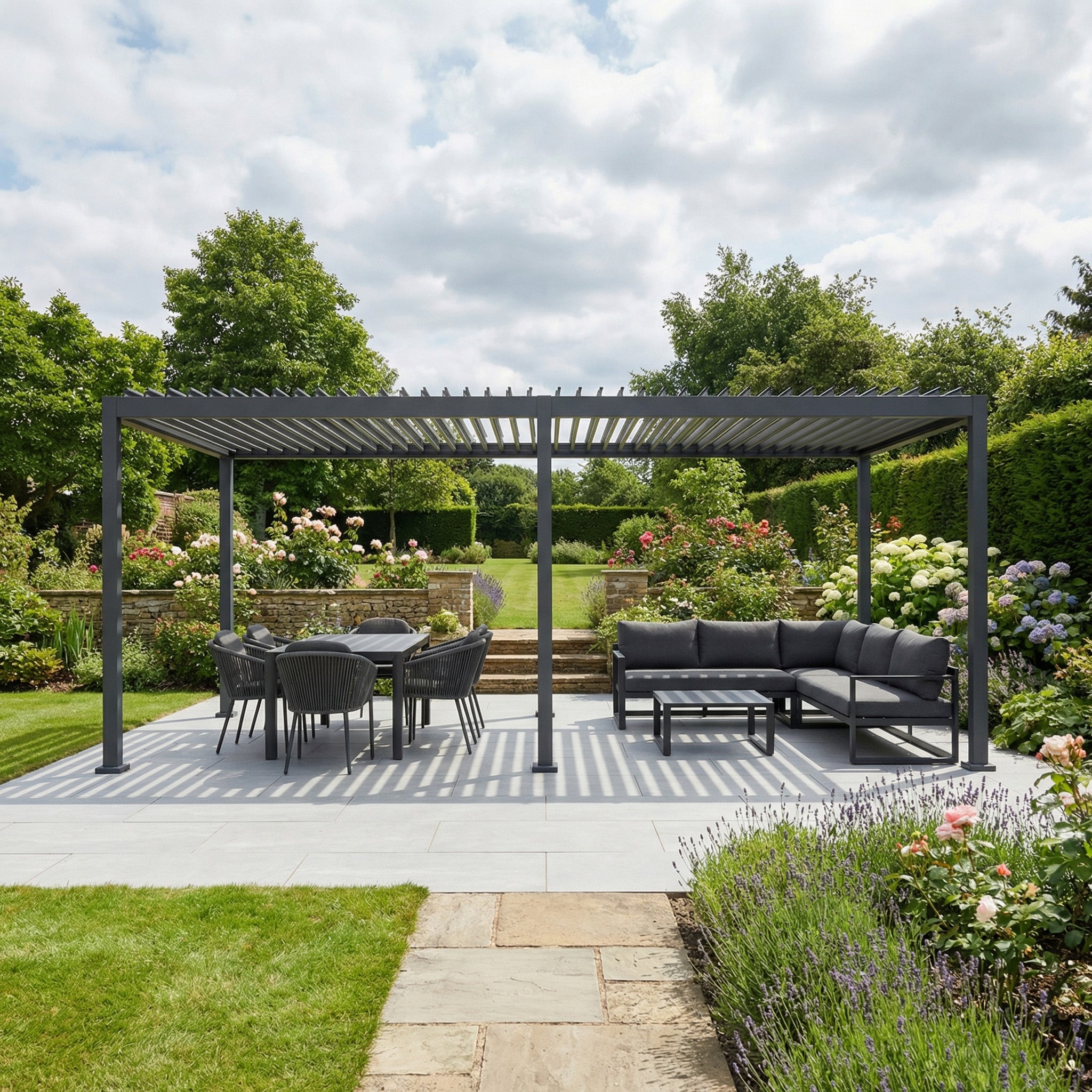 Modern patio featuring the PergoSTET Lite Neo 3m x 6m Metal Rectangular Pergola in Grey, a dining set, and sofa set amid a lush flower-filled garden.