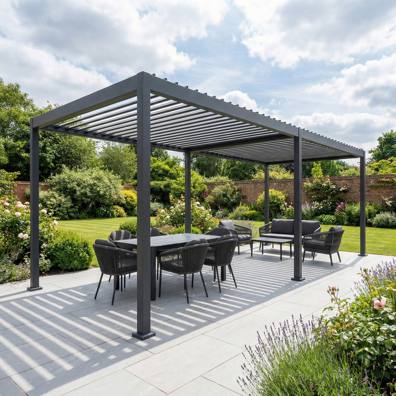 The PergoSTET Lite Neo 3m x 7m Grey Metal Rectangular Pergola creates a stylish patio dining and seating area with tilting louvres for flexible sun control, set against a lush green garden backdrop.