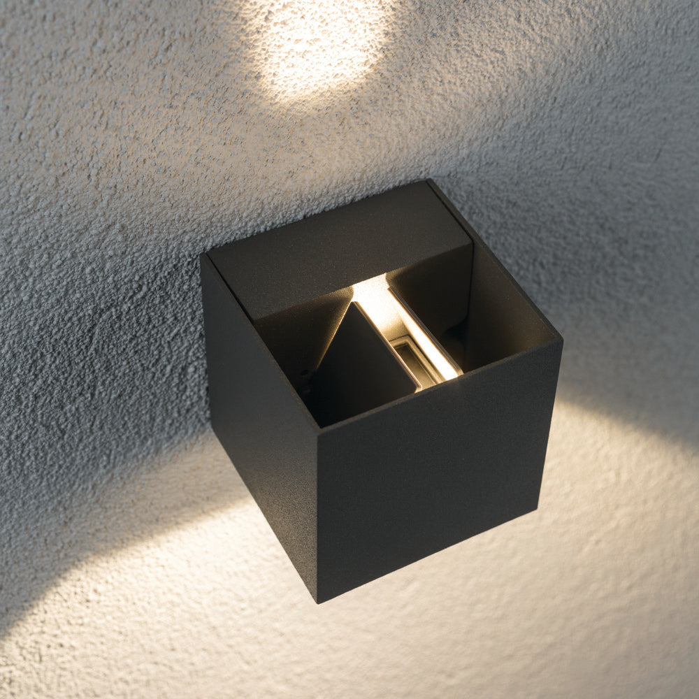 The Paulmann Outdoor Cybo 7.7W LED 8x8cm Wall Light in Grey is a wall-mounted, cube-shaped luminaire that beautifully projects light both upwards and downwards, creating stunning effects on textured surfaces. Its adjustable beam angle provides personalized illumination to complement any ambiance.
