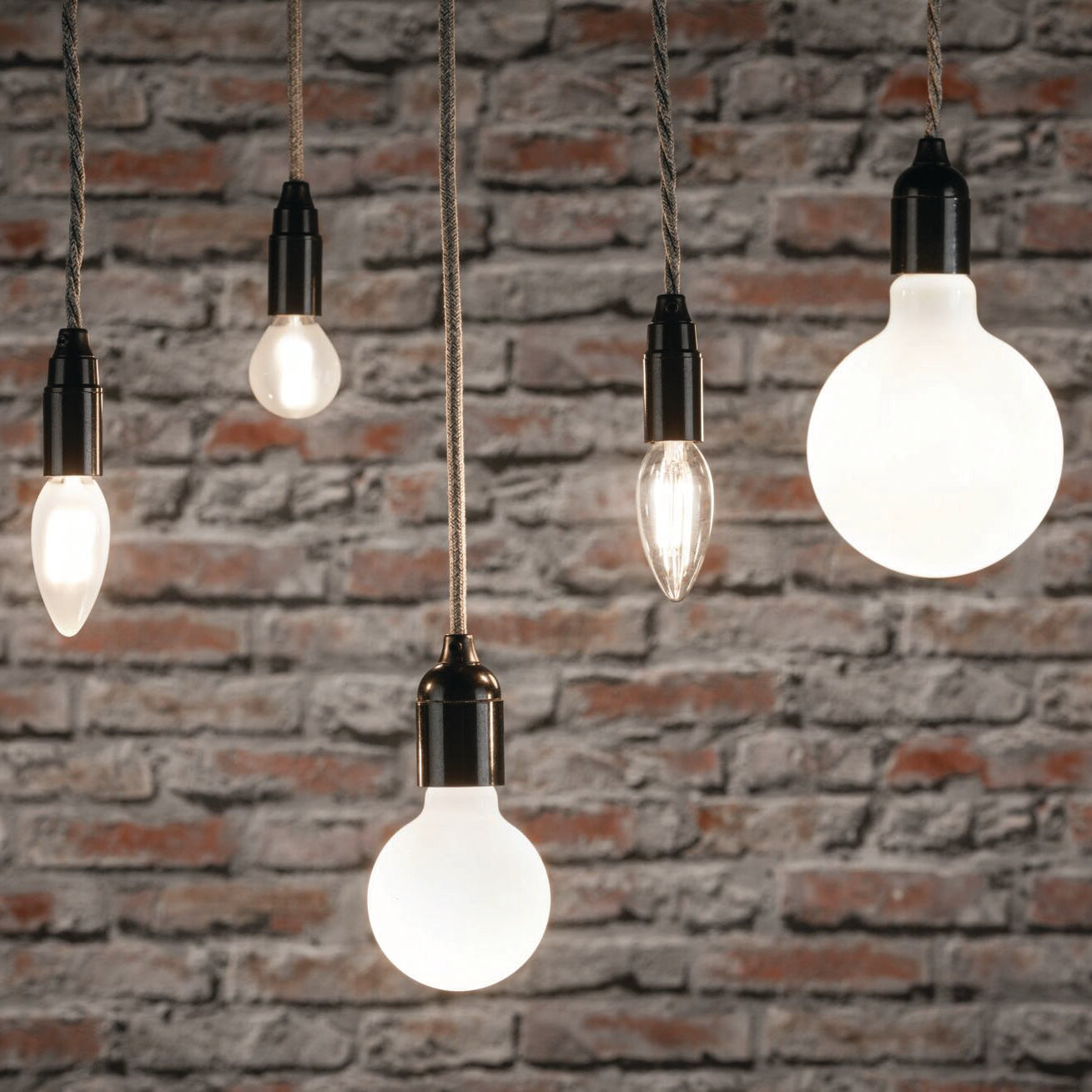 The Paulmann Filament LED Pear Bulb 5W E27 in Warm White light enhances a cozy ambiance against a textured brick wall, fitting seamlessly into E27 sockets for a stylish touch.