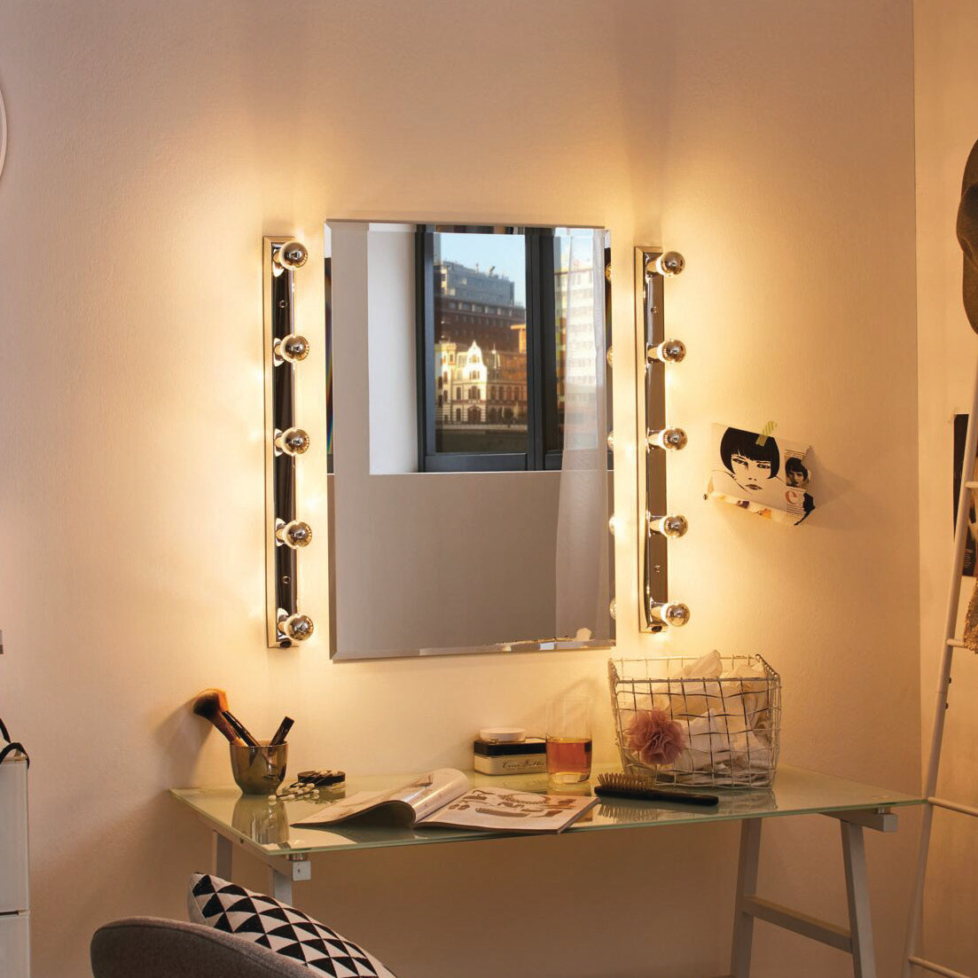 The Paulmann Standard LED Drop Crown Mirror Bulb 2.6W E14 Silver casts a warm white glow, elegantly illuminating the vanity mirror above the glass desk, where books and a stylish pen holder are neatly arranged.
