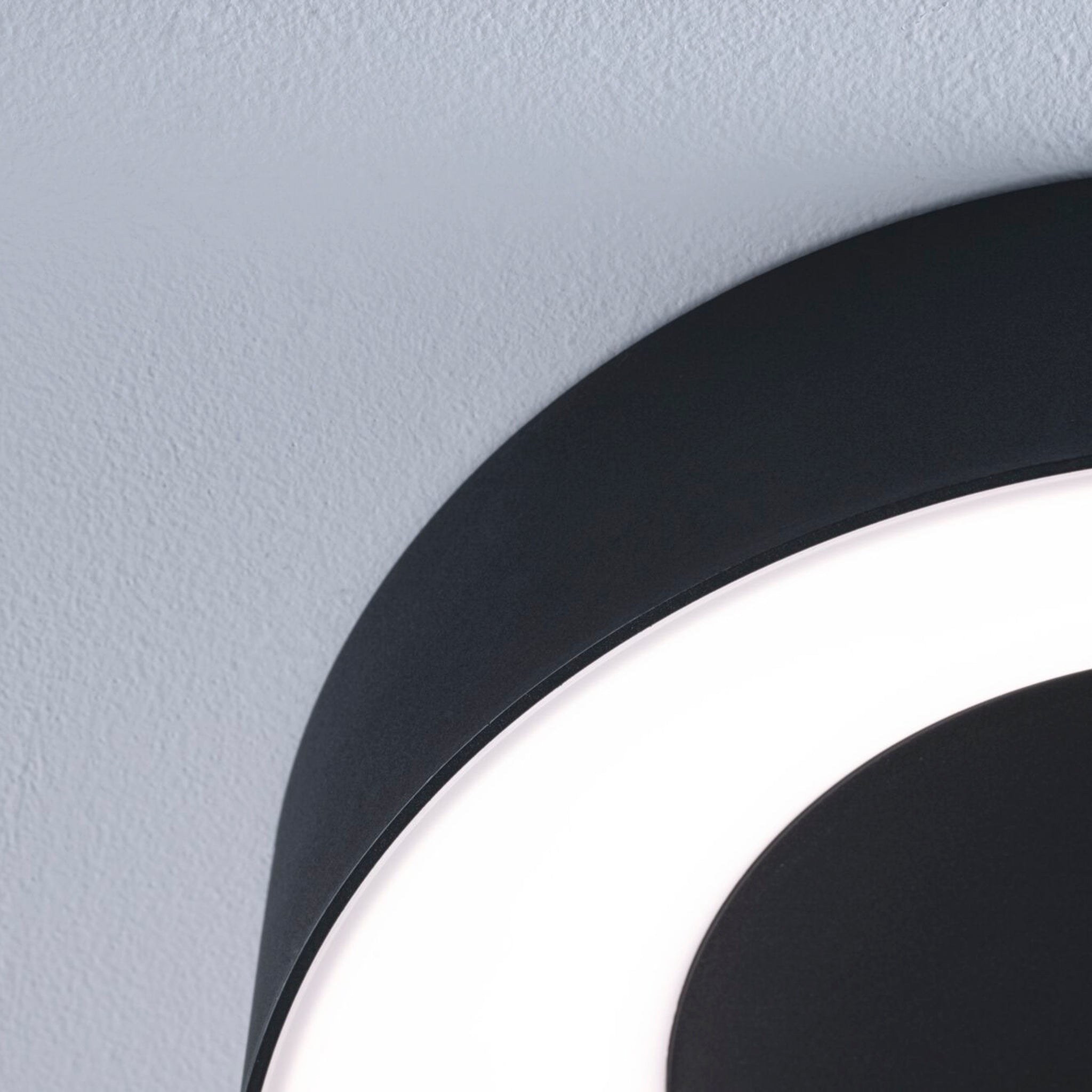 A close-up of the Paulmann Casca 18W LED Switch Ceiling Light in Black Matt, installed on a white ceiling, highlighting its elegant lighting effect.
