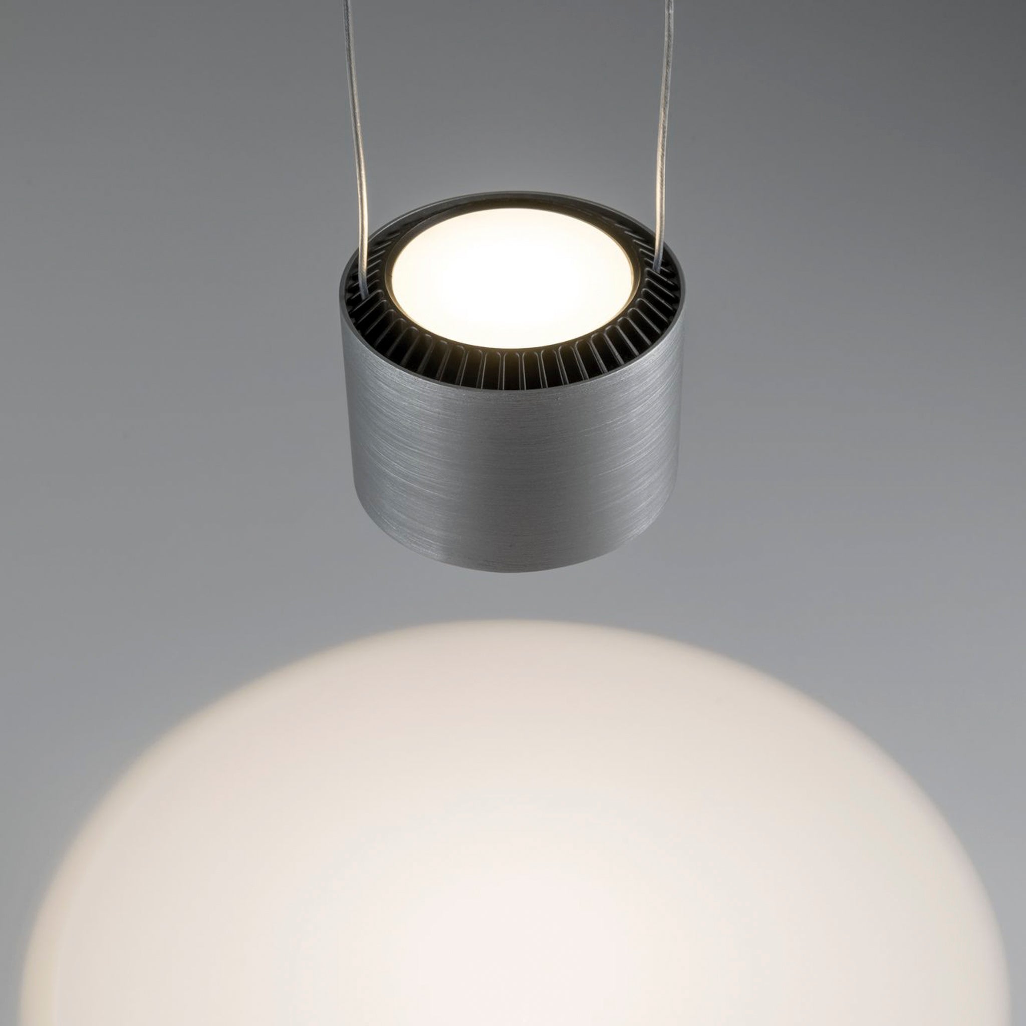 The Paulmann Aldan 28W LED dimmable pendant light in brushed aluminium is a contemporary fixture with three lamps and adjustable pendant lengths, offering a glowing bulb that casts a gentle light on the surface below.