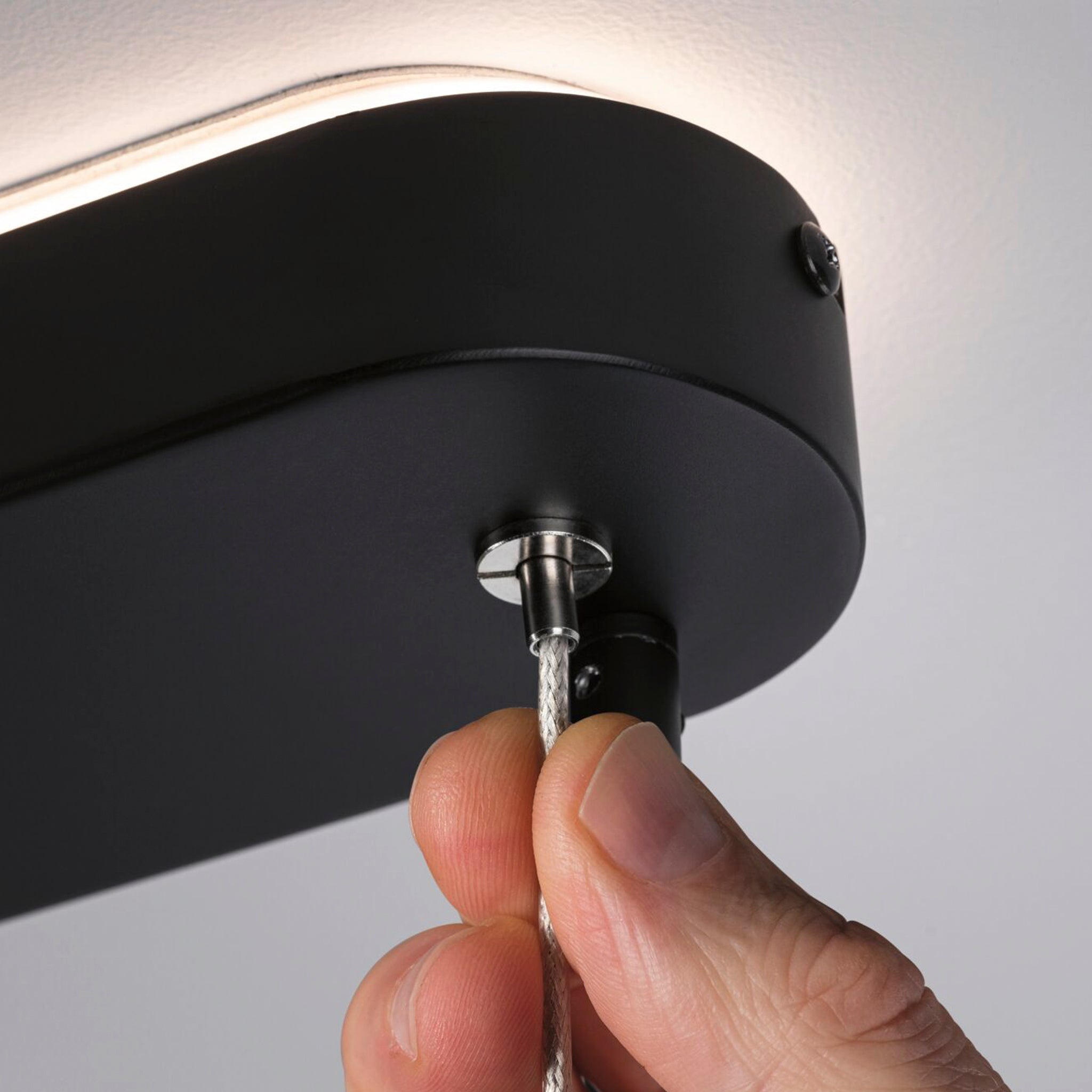 Close-up of a hand adjusting the Paulmann - Puric Pane 6.5W LED 6 Lamp Pendant Light in black, showcasing its 3-step dimmable lighting feature.