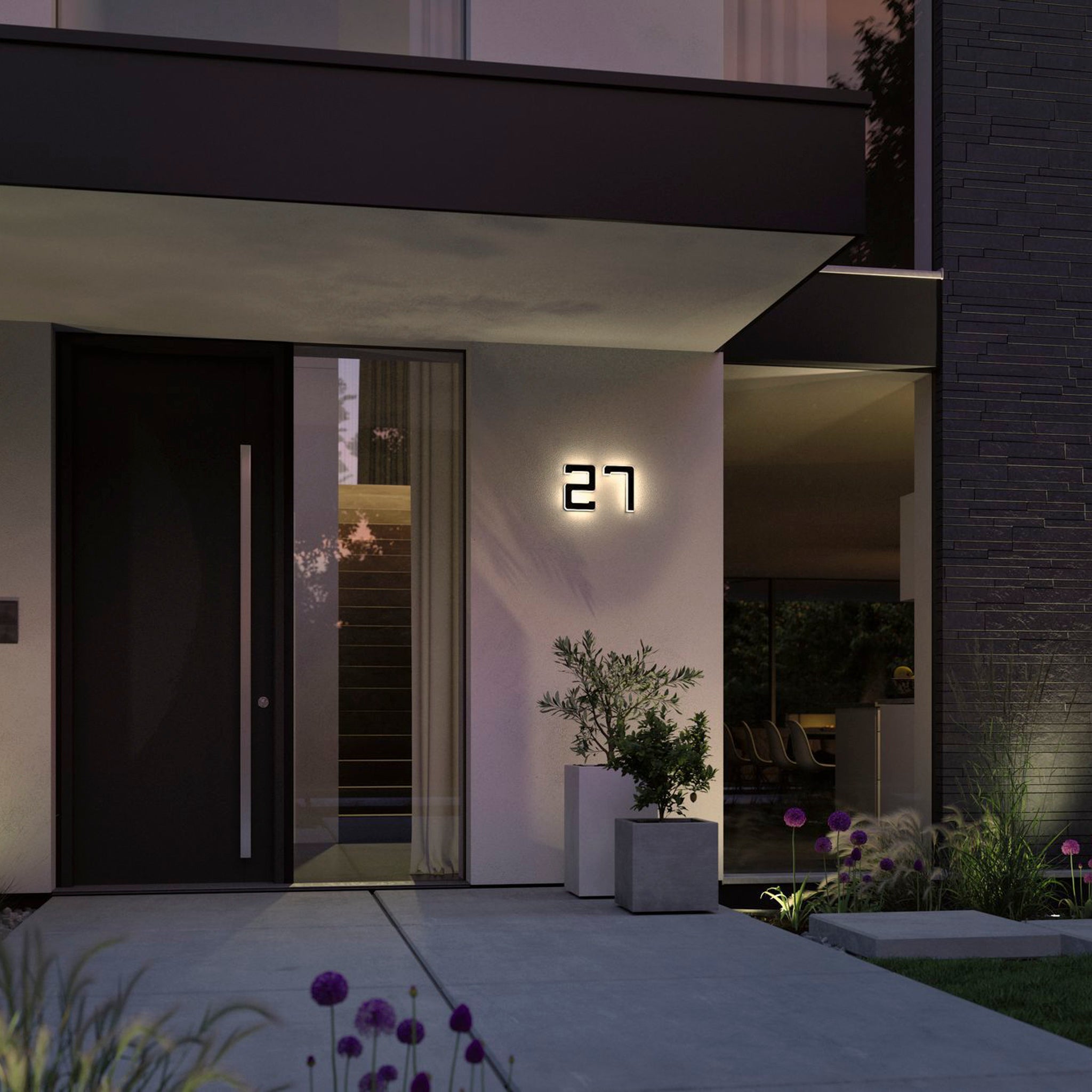 Modern house entrance featuring the Paulmann Outdoor Solar House Number 2 LED 0.2W with a replaceable battery in black, displaying the illuminated number 27, alongside a large door and planters at dusk.