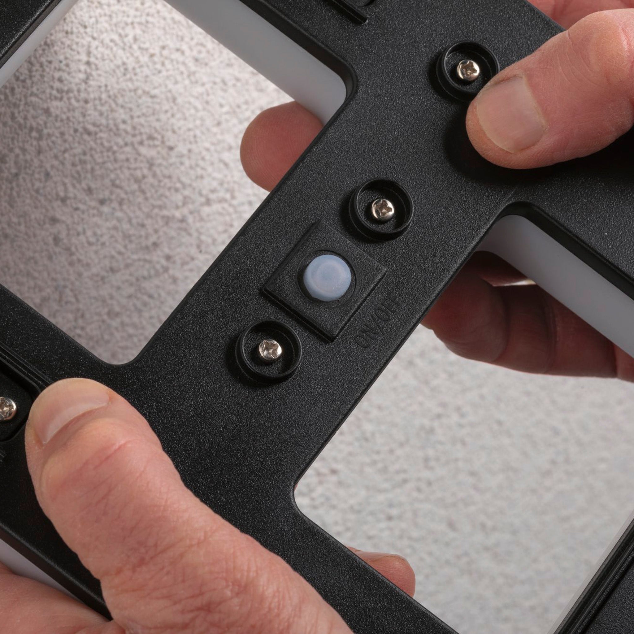 Hands adjusting the Paulmann Outdoor Solar House Number 3 LED 0.2W, complete with a replaceable battery in black, against a textured wall, transforming it into an elegant solar-powered luminaire.
