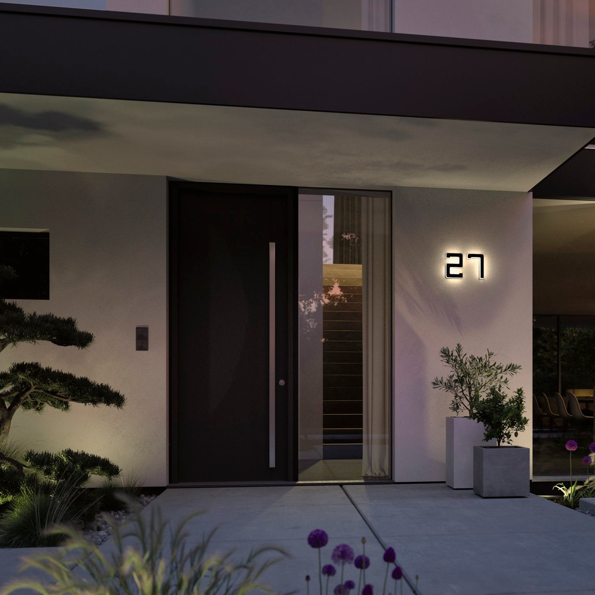 The modern house entrance showcases a sleek black door complemented by the Paulmann Outdoor Solar House Number 7 LED 0.2W with a replaceable battery, displaying an illuminated number "27." Surrounded by plants and evening lighting, the scene is elegantly sustainable with solar-powered fixtures.